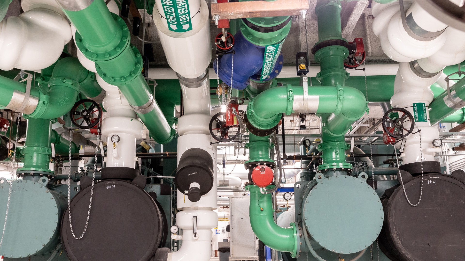 Industrial green and white pipeline system with valves and gauges Industrial green and white pipes with valves and gauges in a mechanical room.
