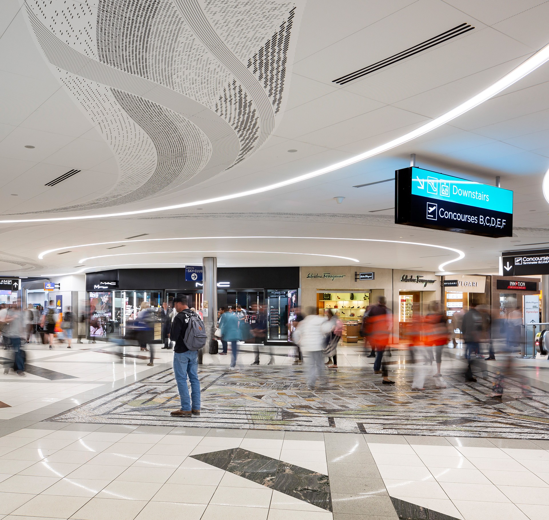 Modern Airport Terminal with Shops and Directional Signs Busy airport terminal with travelers and shops under curved ceiling lights and signs.