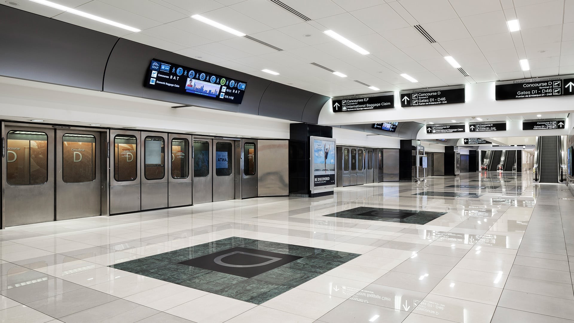Modern airport train station with clean, polished floors and clear directional signs.