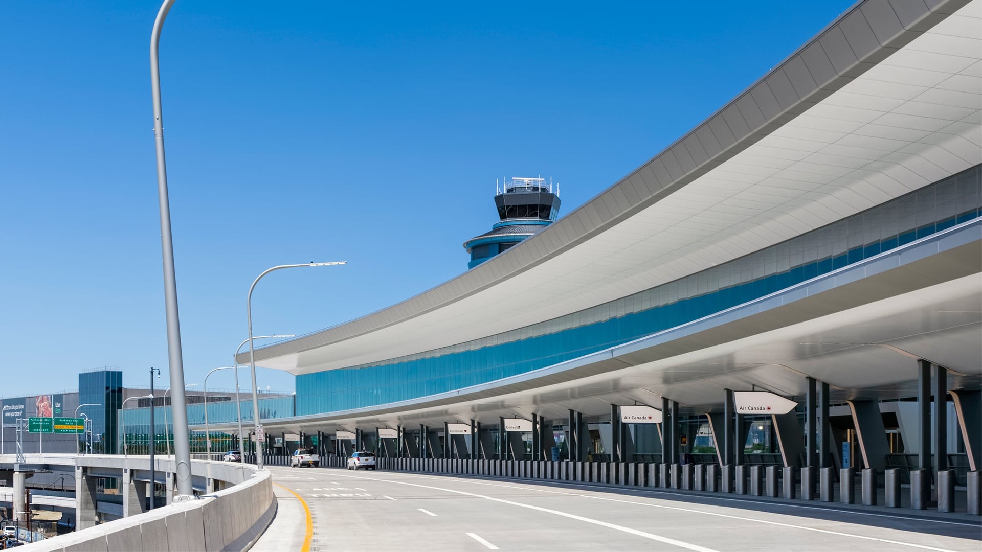 Modern airport terminal with clear skies and control tower in the background.