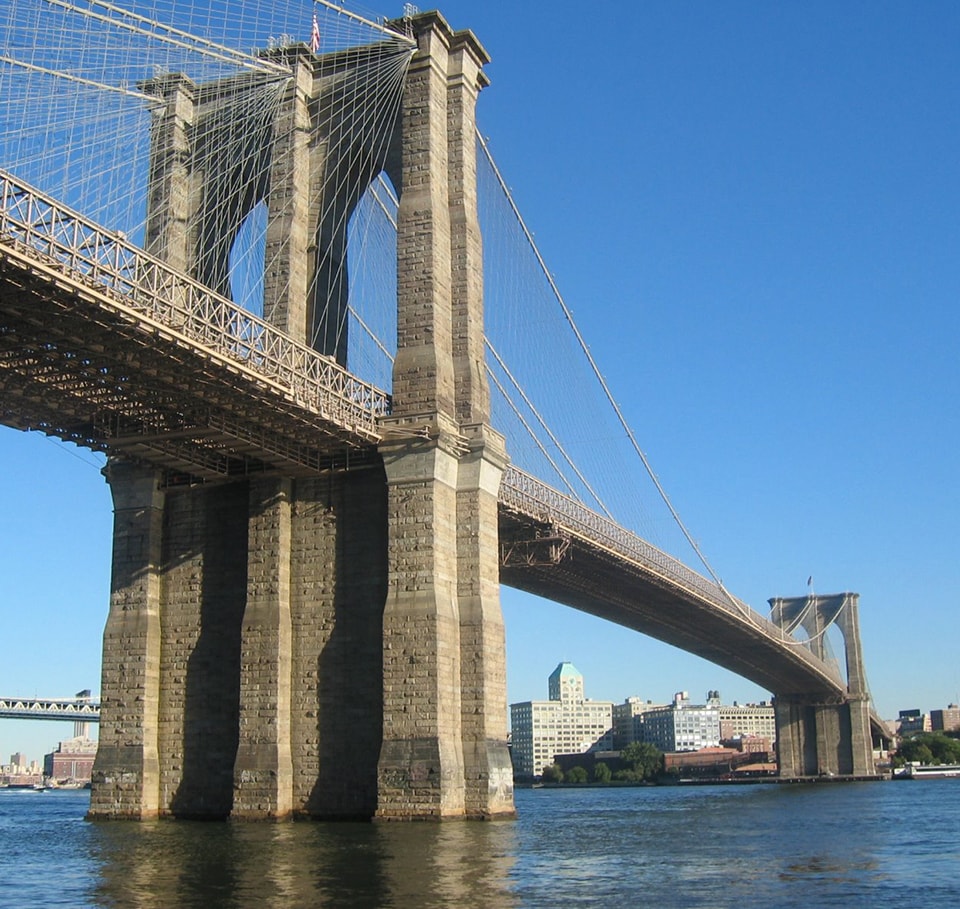 Brooklyn Bridge spanning the East River with clear blue sky in New York City.
