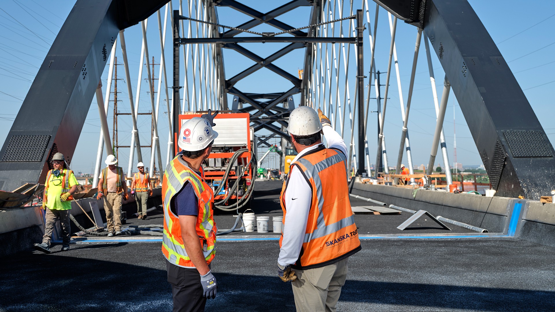 Bridge Construction Workers Inspecting Progress on Site Construction workers in safety gear inspecting bridge framework during roadwork.