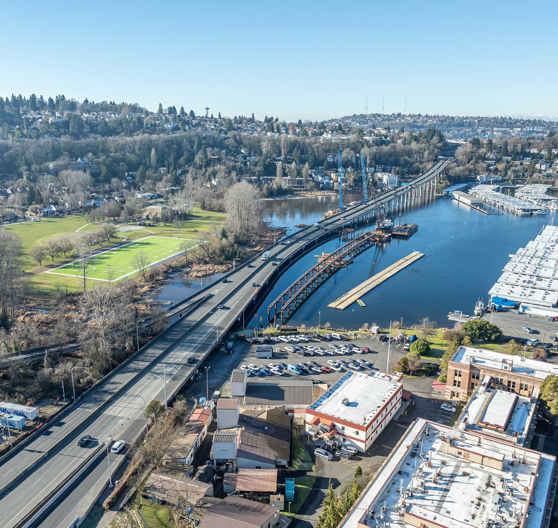 Scenic Bridge and Waterfront Area with Urban Landscape View Aerial view of a highway bridge under construction over a river with surrounding buildings.