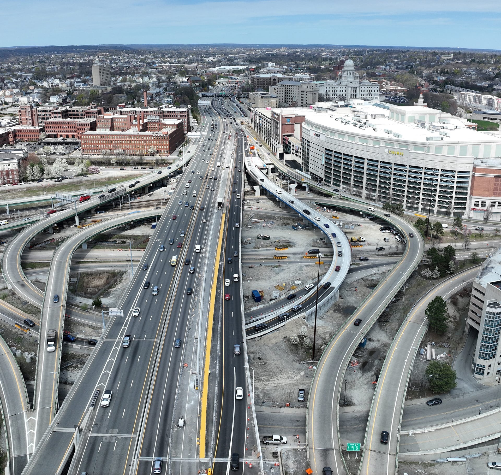 Aerial view of a busy multi-lane highway interchange with surrounding cityscape.