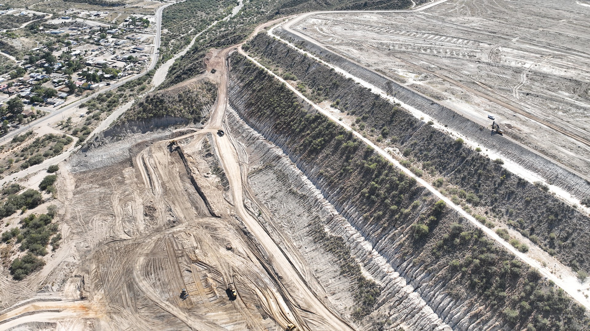 Aerial view of large-scale earth excavation and construction site with heavy machinery.