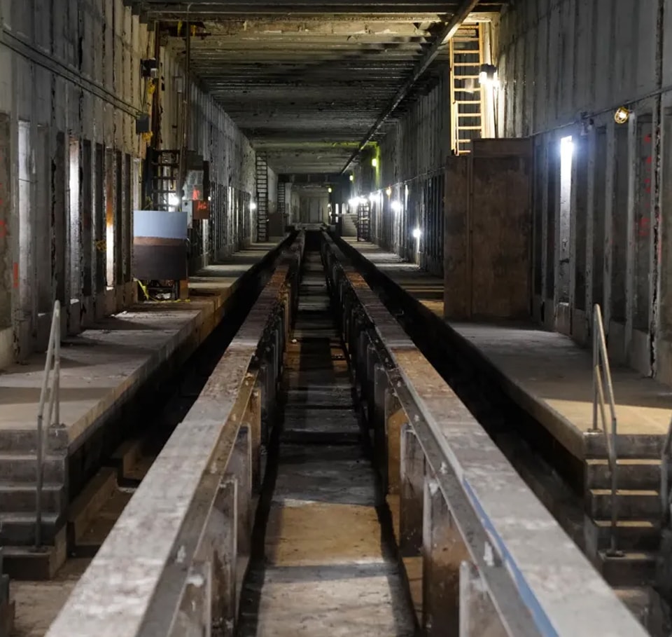 Abandoned Industrial Tunnel with Metal Rails and Staircases Underground industrial tunnel with metal rails and dim lighting for maintenance access.