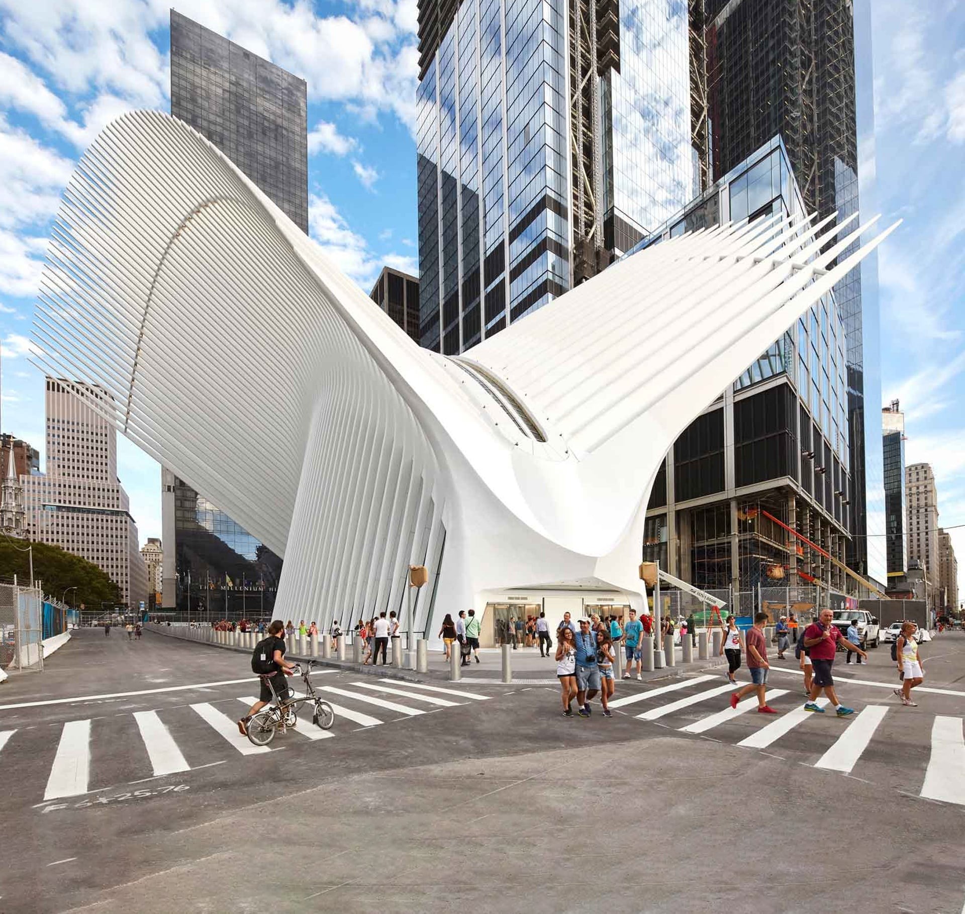 Modern white architectural structure with wing-like design in urban cityscape.