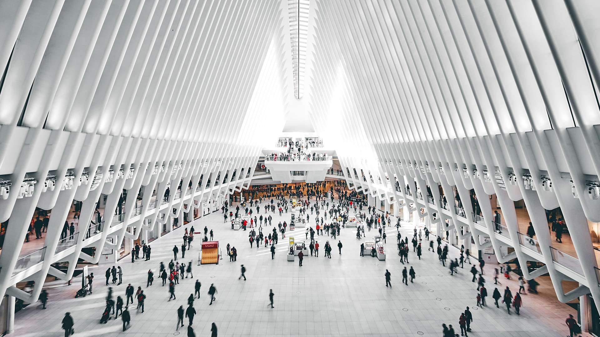 Interior view of a modern, spacious transit hub with people walking inside.