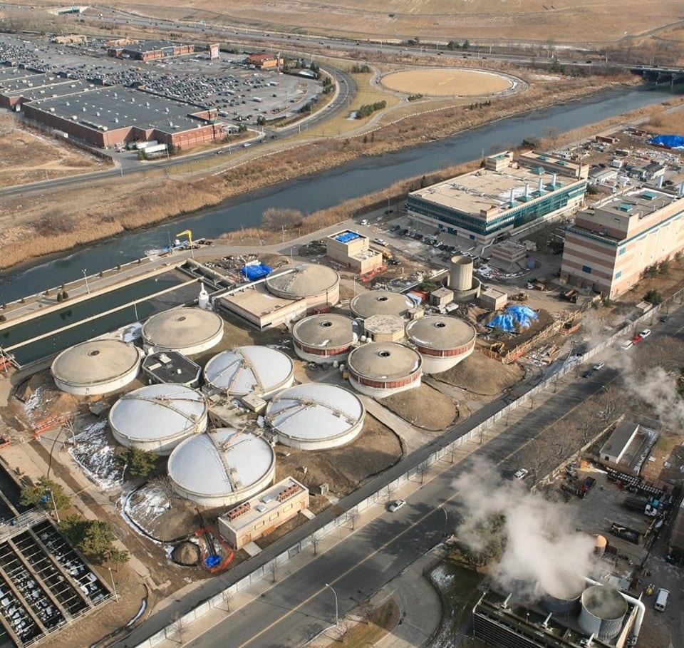 Aerial view of an industrial water treatment plant with large circular tanks and buildings.