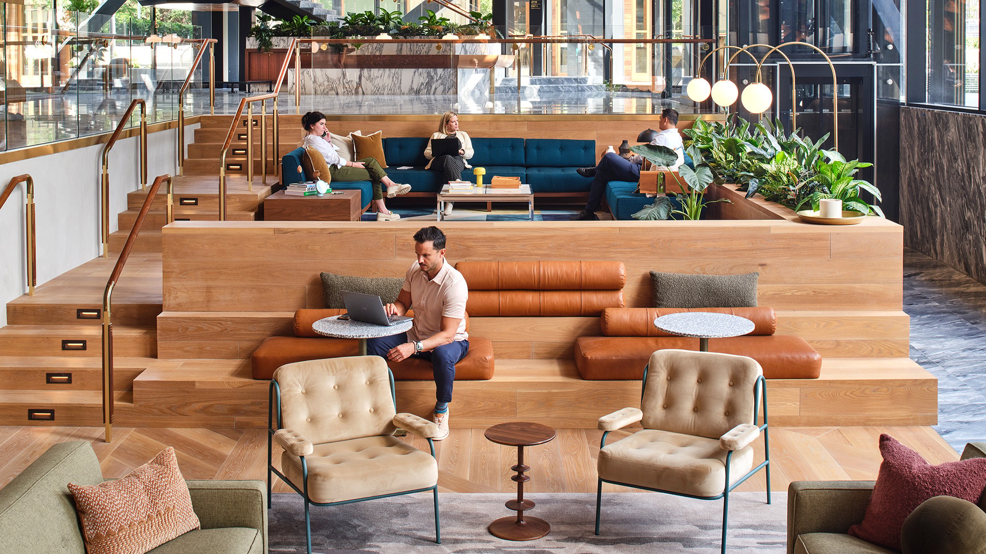 Modern co-working space with tiered seating, plants, and people working on laptops.