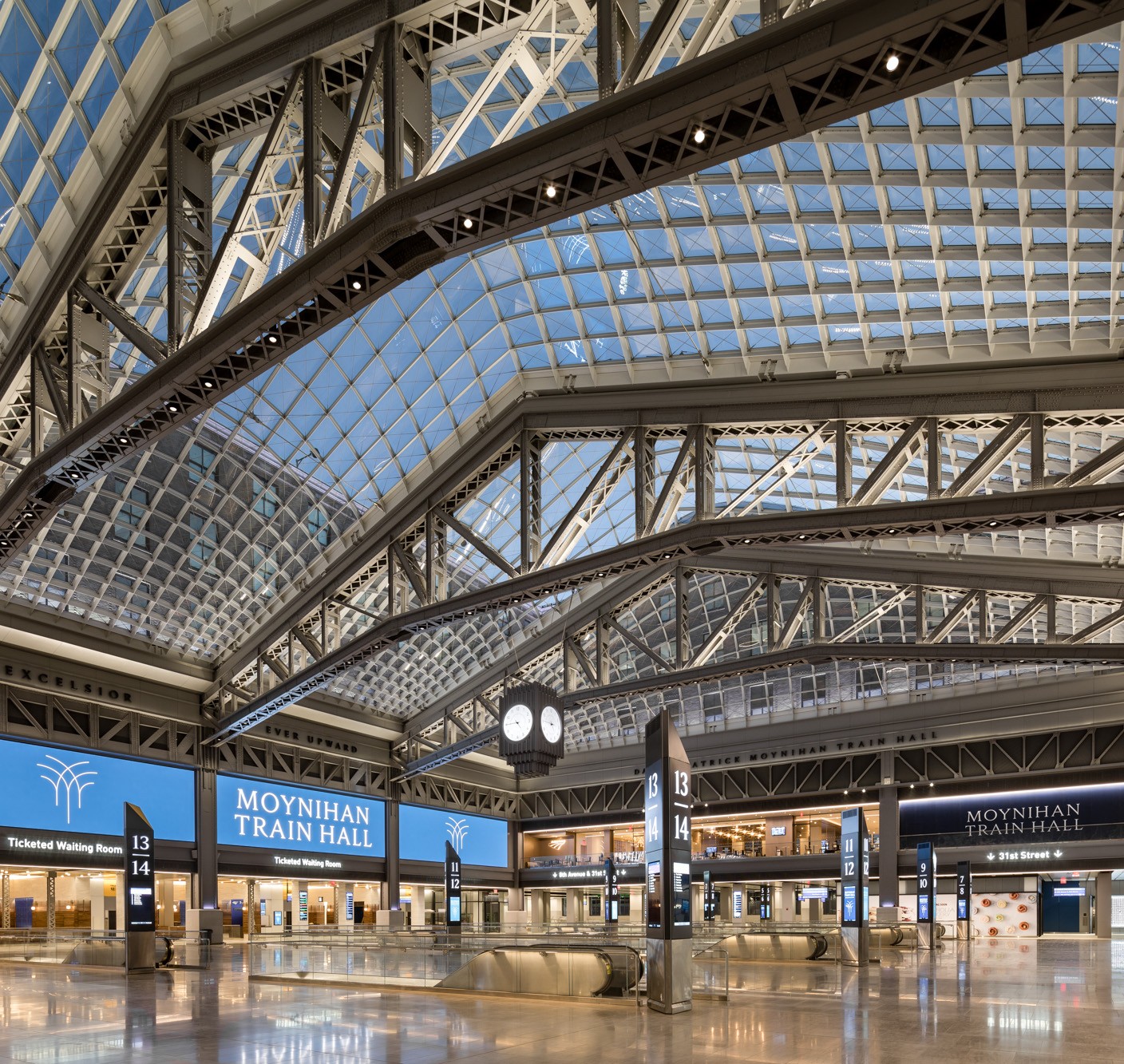 Interior view of Moynihan Train Hall with glass ceiling and modern steel architecture.