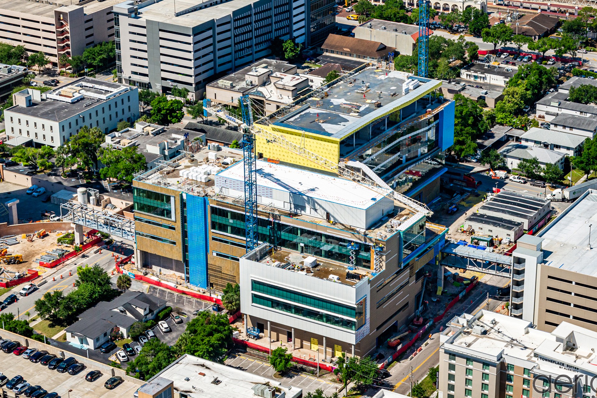Urban construction site with cranes and modern buildings. Aerial view of a multi-story hospital under construction in an urban area with cranes.