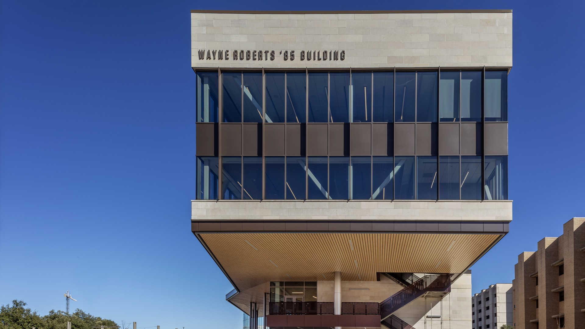 Modern Wayne Roberts '86 Building with glass windows against clear blue sky.