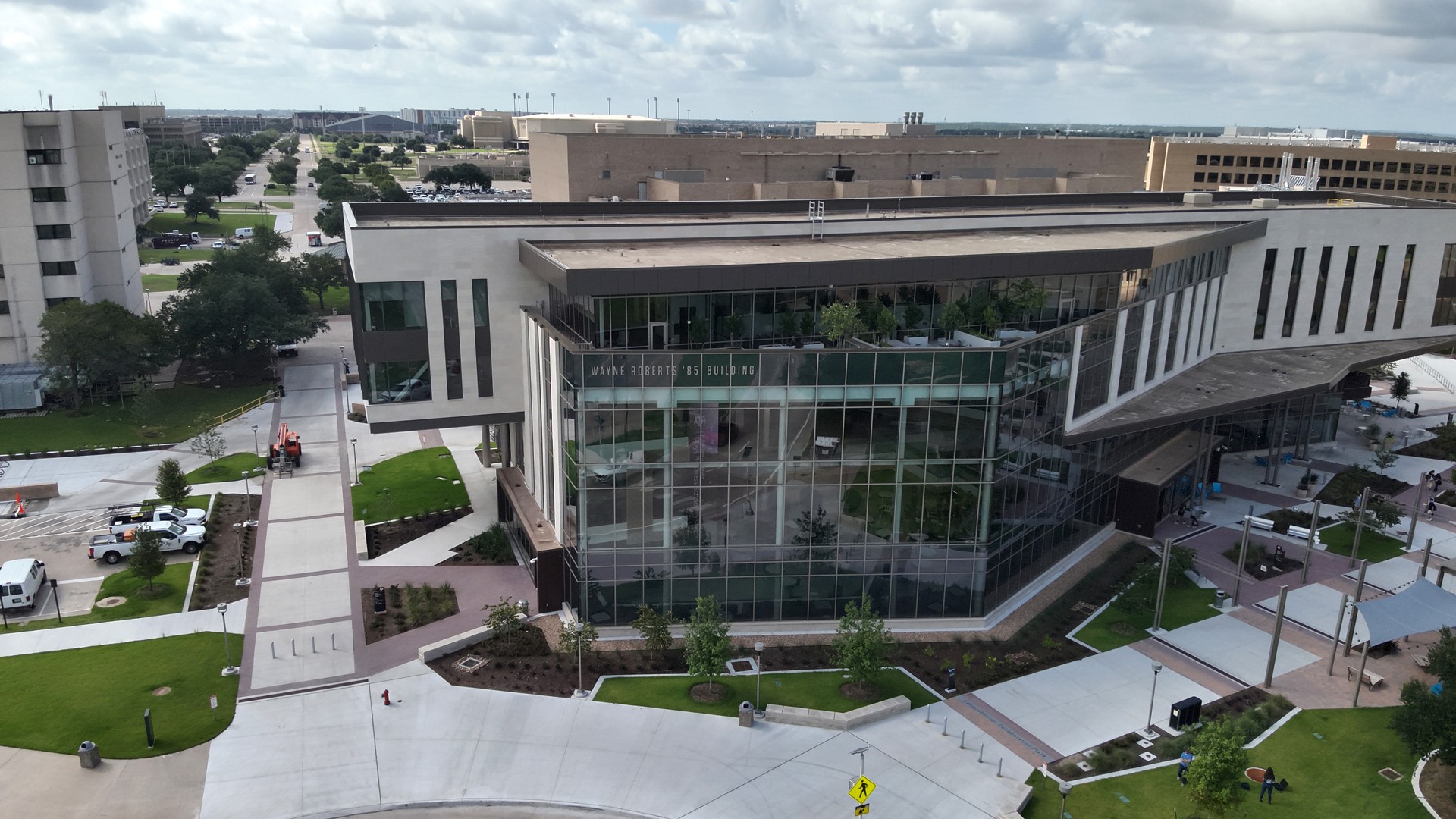 Modern office building with large glass windows and surrounding green landscaping.