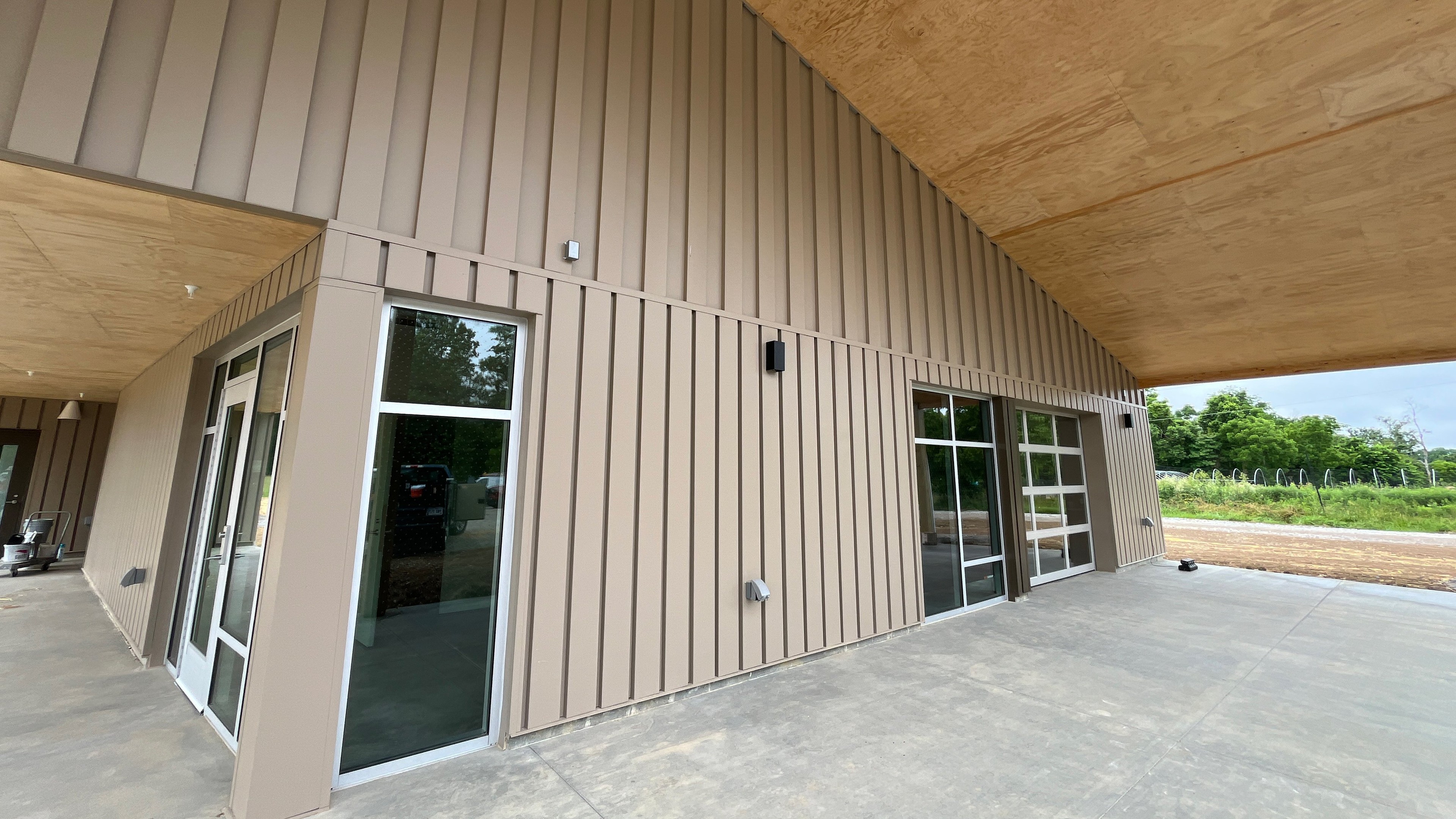 Modern building exterior with glass doors and concrete patio Modern beige metal building exterior with large glass doors and concrete patio.