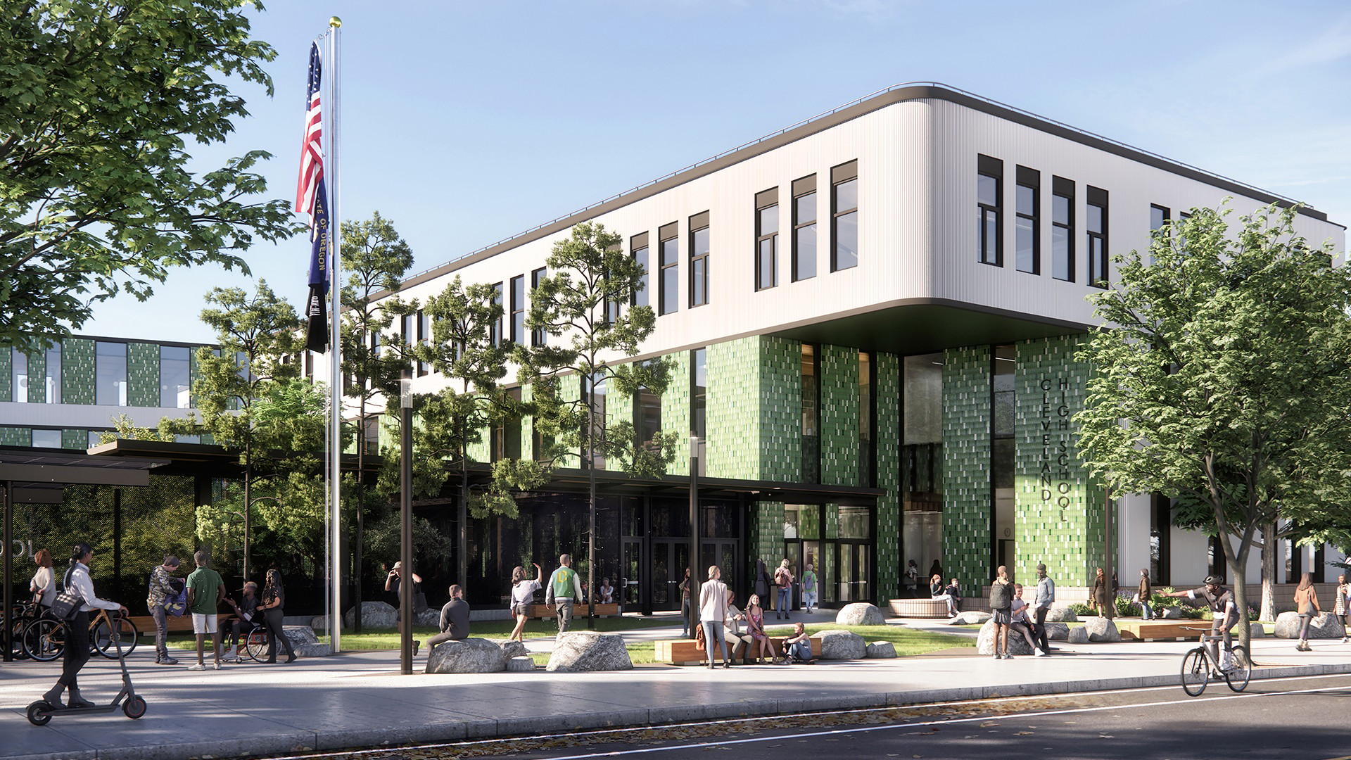 Modern school building with green tiles, large windows, and people outside on a sunny day.