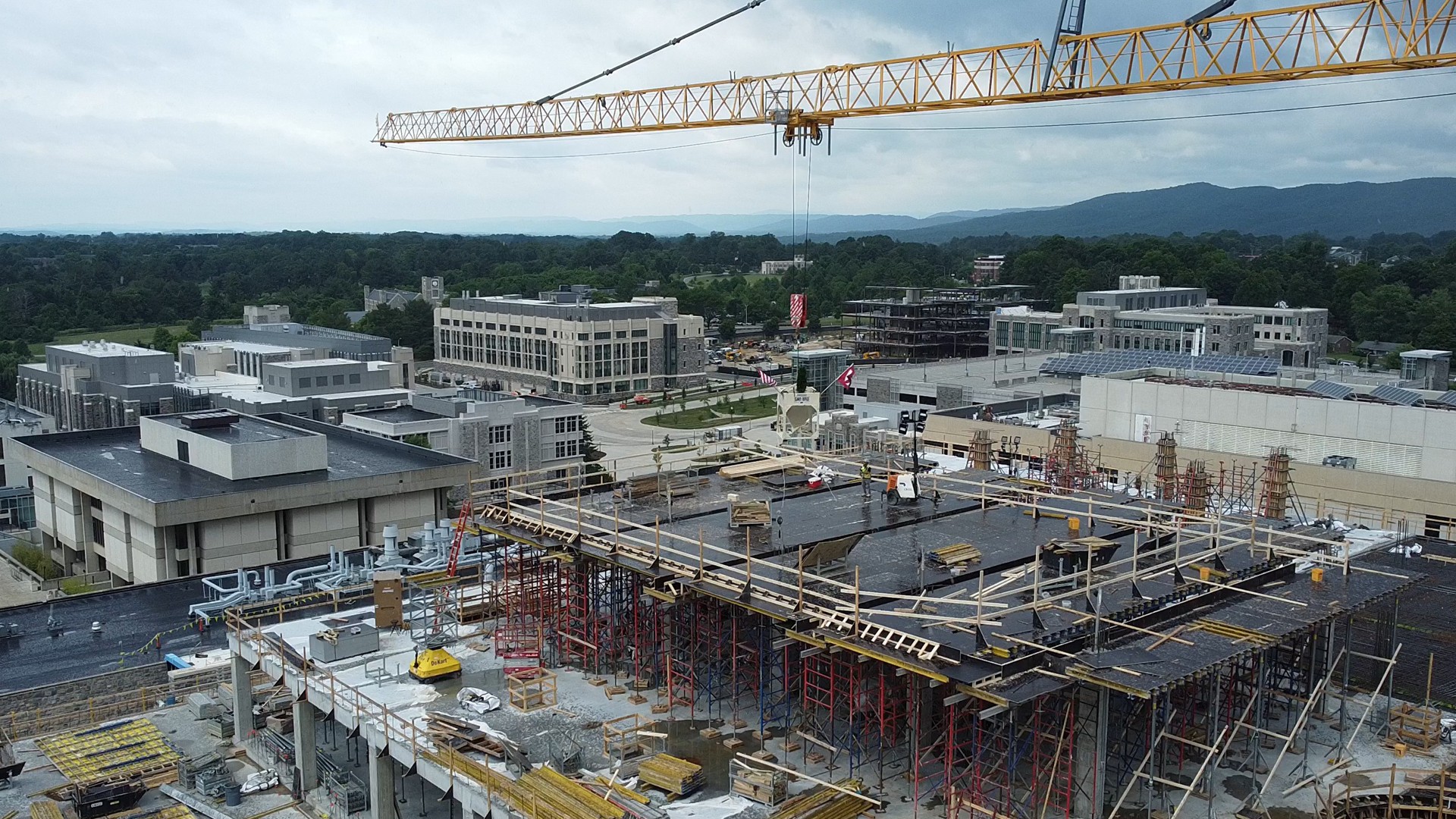 Construction site with cranes and scaffolding in an urban area under cloudy sky.