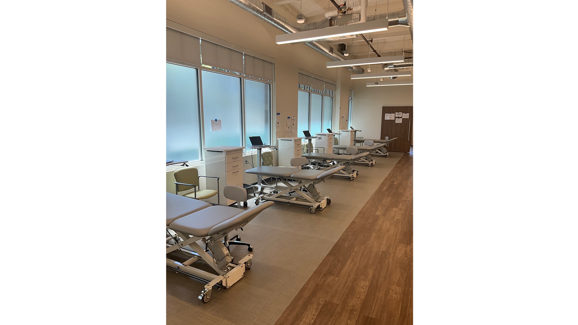 Modern physical therapy clinic with treatment tables, chairs, and medical equipment.