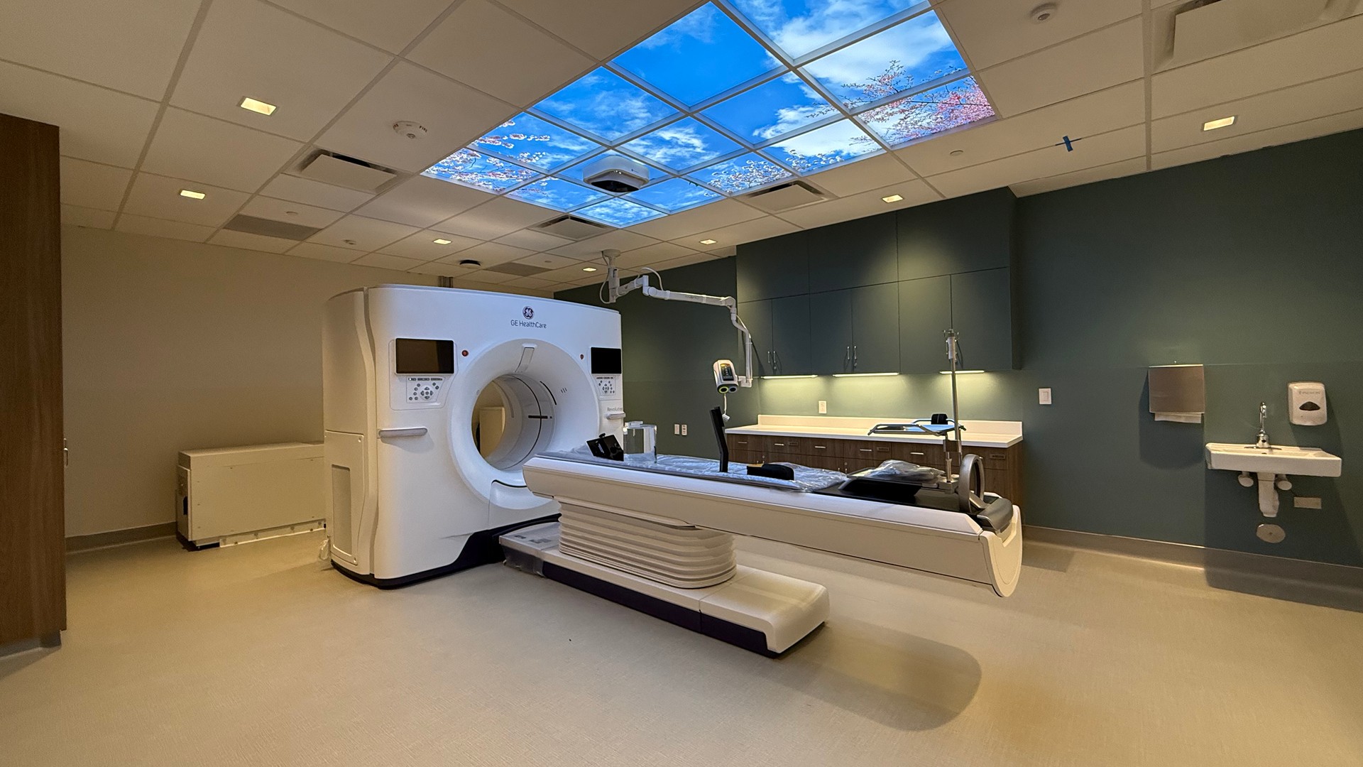 Modern MRI machine in a clean, well-lit medical imaging room with blue ceiling panels.