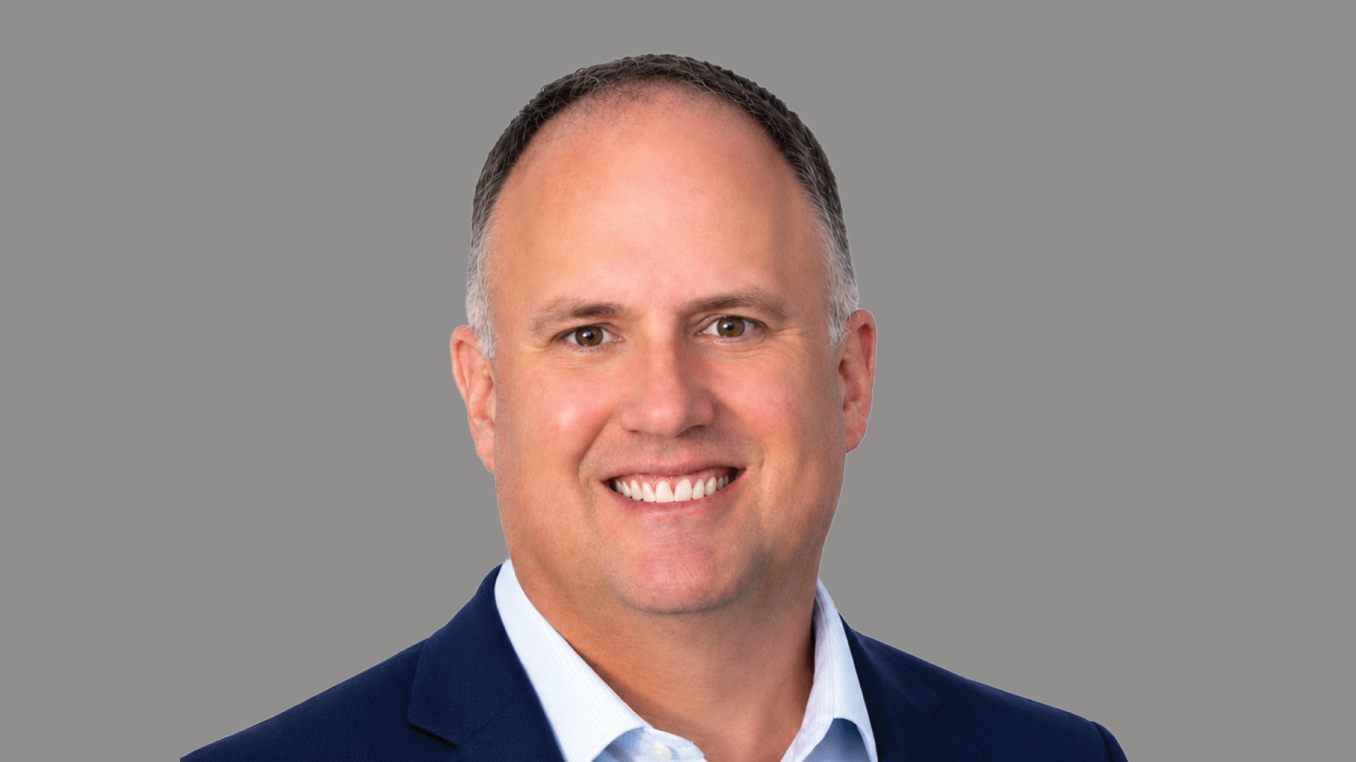 Professional Businessman Smiling in Blue Suit with Gray Background Professional headshot of a smiling middle-aged man in a blue suit with gray background.