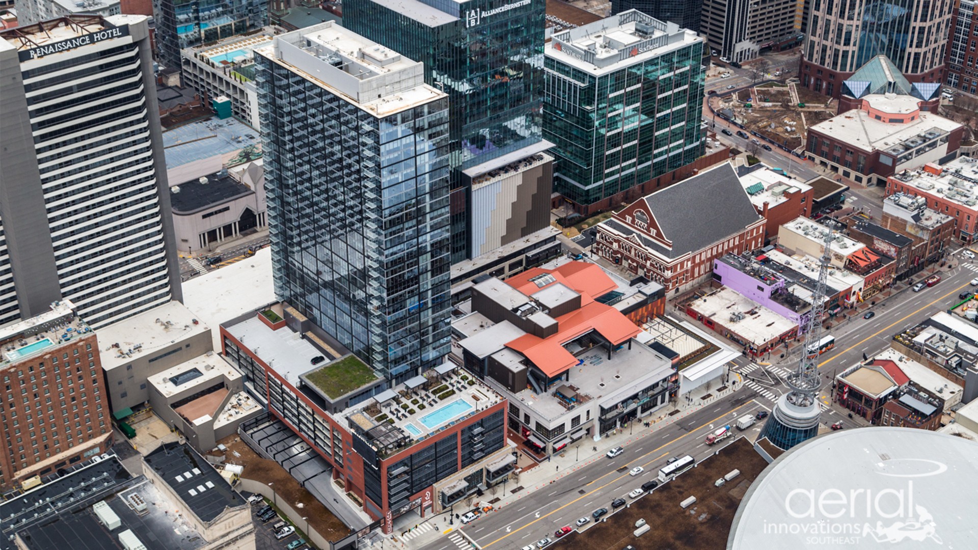 Aerial view of a city block with modern glass buildings, roads, and traffic.