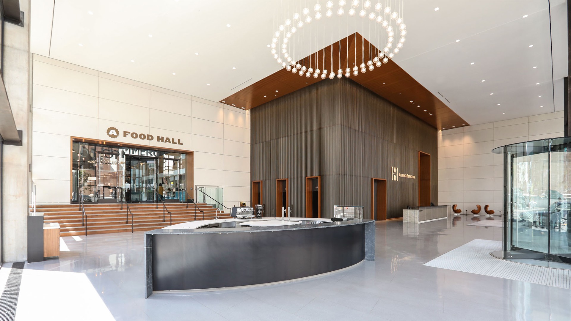 Modern, spacious lobby with a central black reception desk and Food Hall entrance.