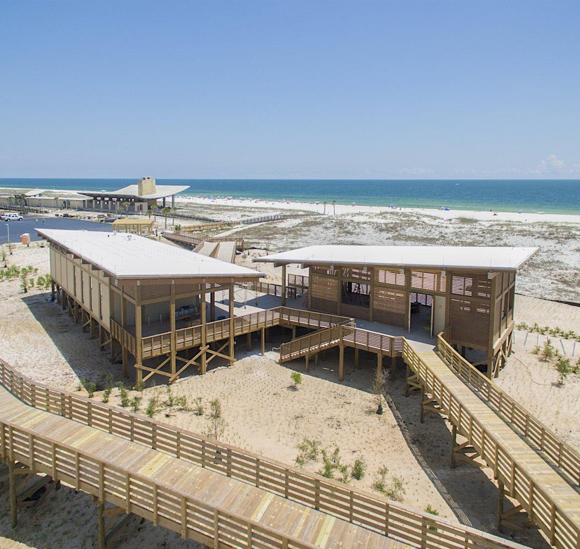 Beachfront wooden buildings with ramps and ocean view under a clear blue sky.