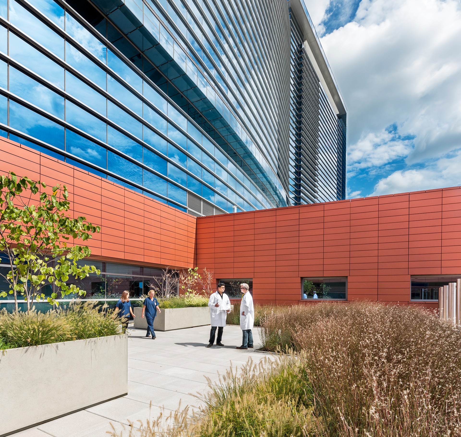 Modern Office Building with Glass and Red Brick Facade Modern commercial building with glass and red brick facade under a partly cloudy sky.