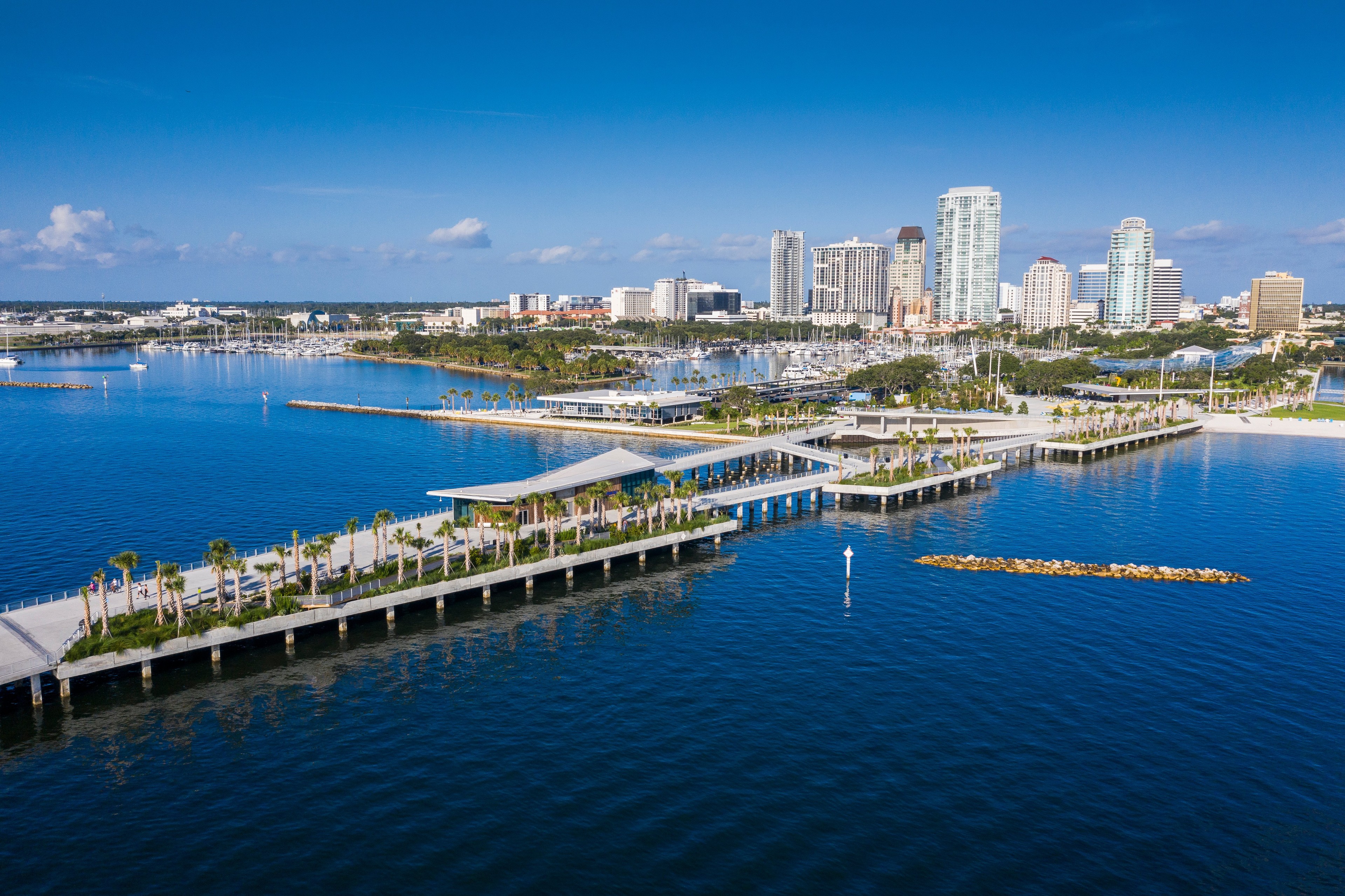 Aerial view of a coastal city with waterfront parks, piers, and modern high-rise buildings.