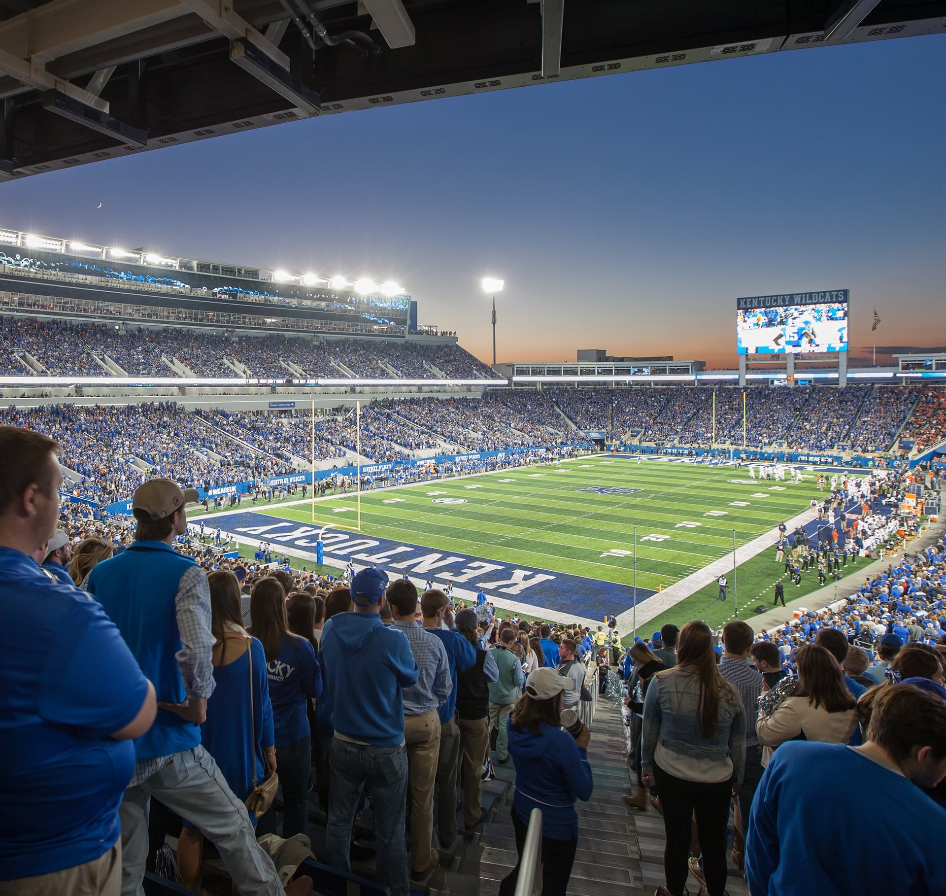 Crowded University of Kentucky football stadium at sunset during a game.