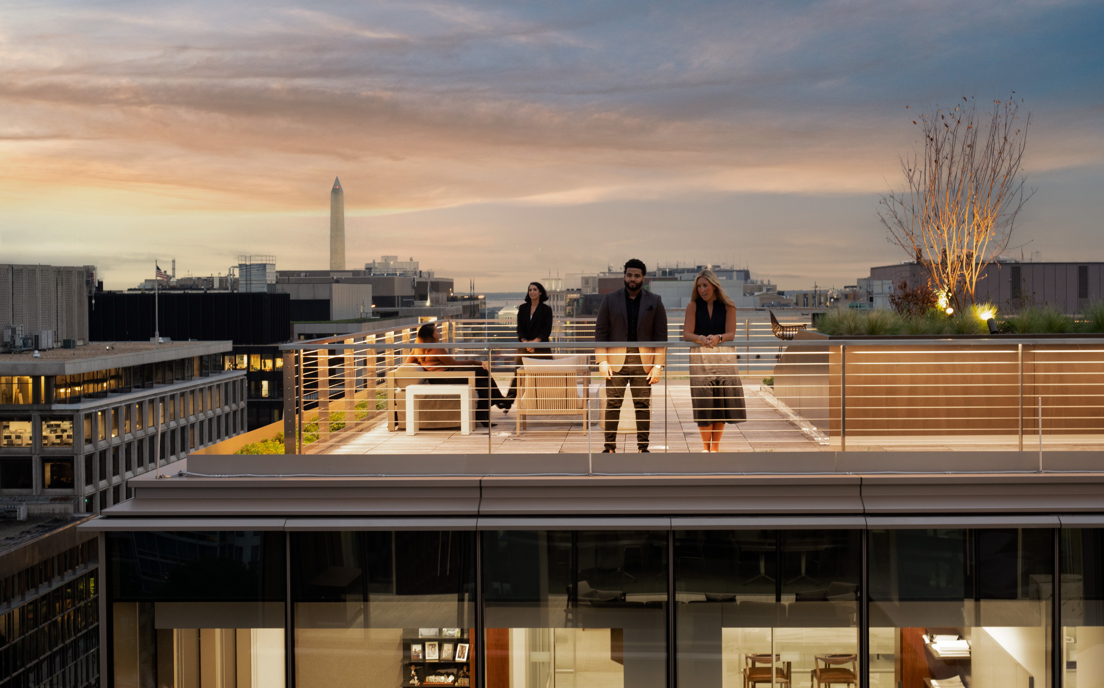 Business professionals networking on a modern rooftop terrace at sunset in the city.