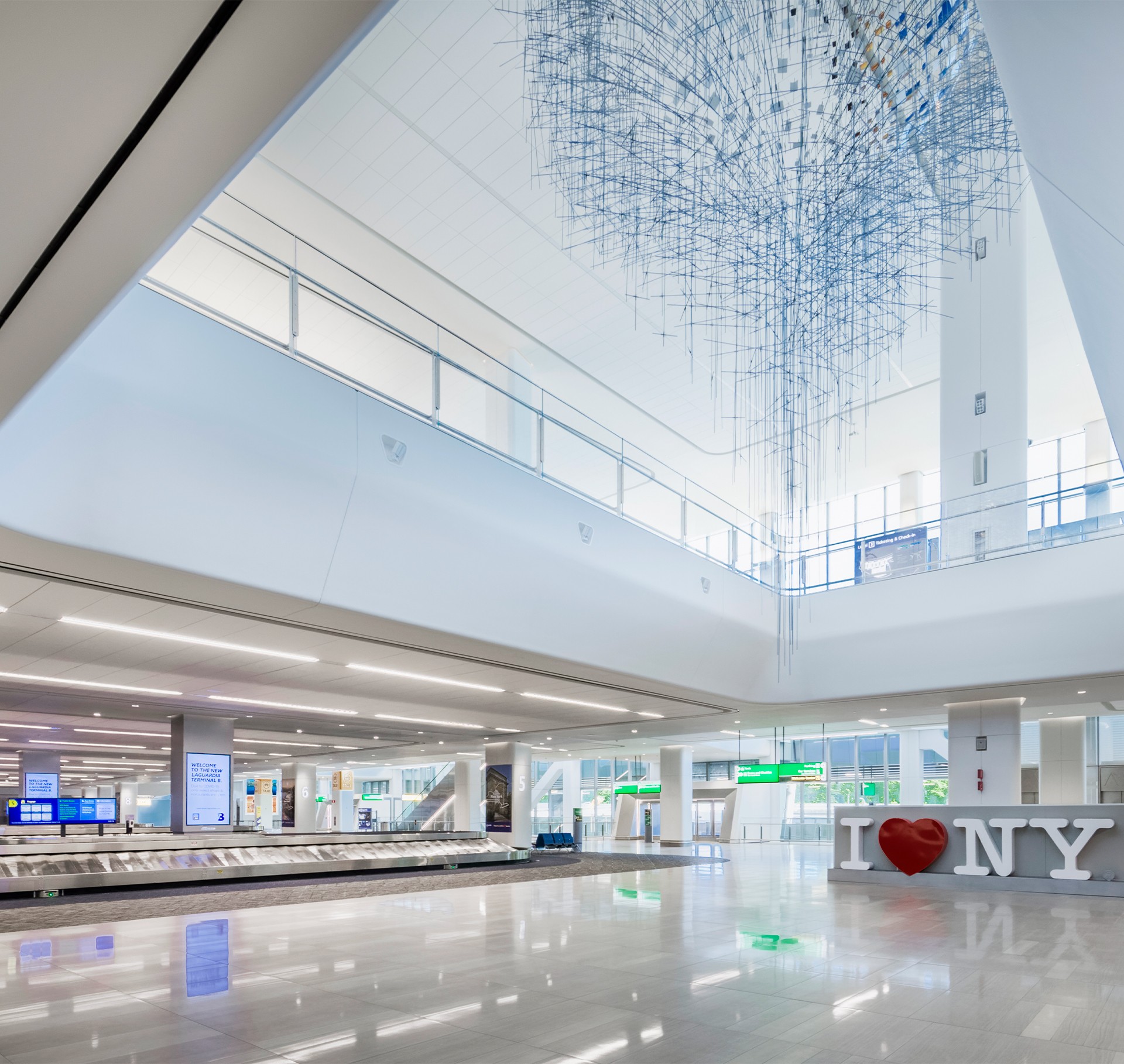 Spacious modern airport baggage claim area with "I ♥ NY" sign and high ceilings.
