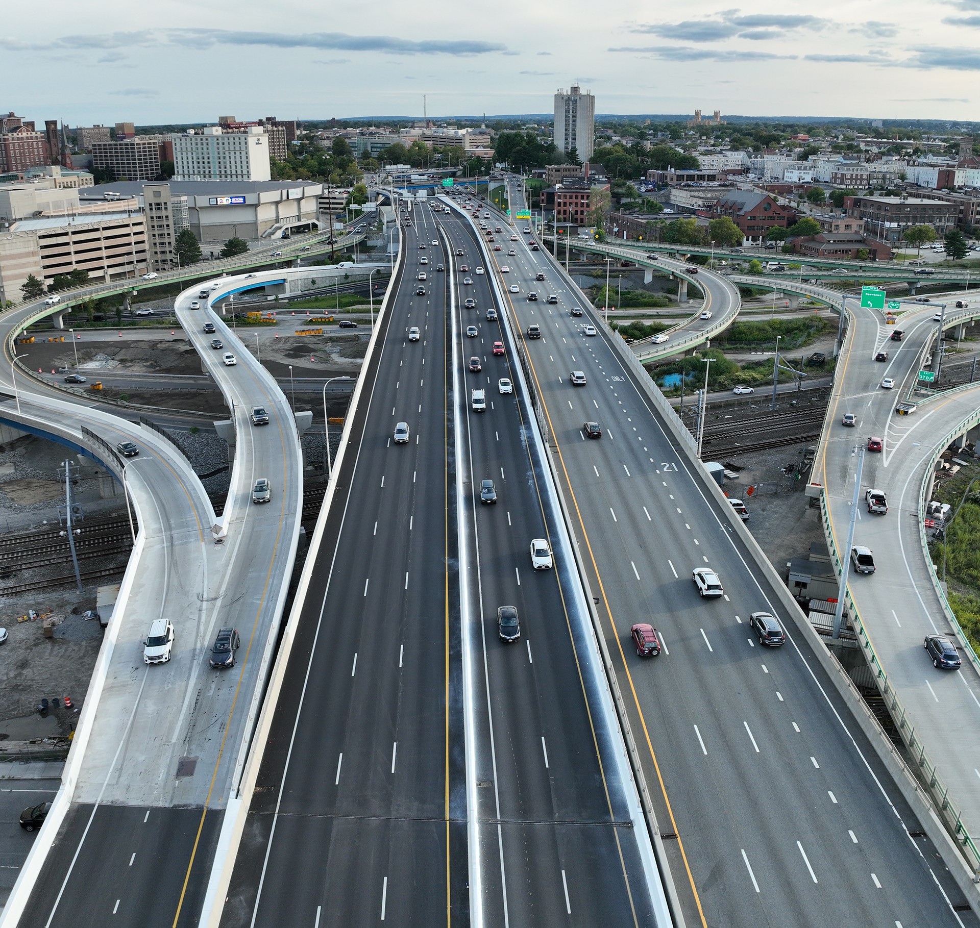 Aerial View of Busy Urban Highway Interchange with Traffic Aerial view of a busy multi-lane highway with curved ramps and urban buildings nearby.