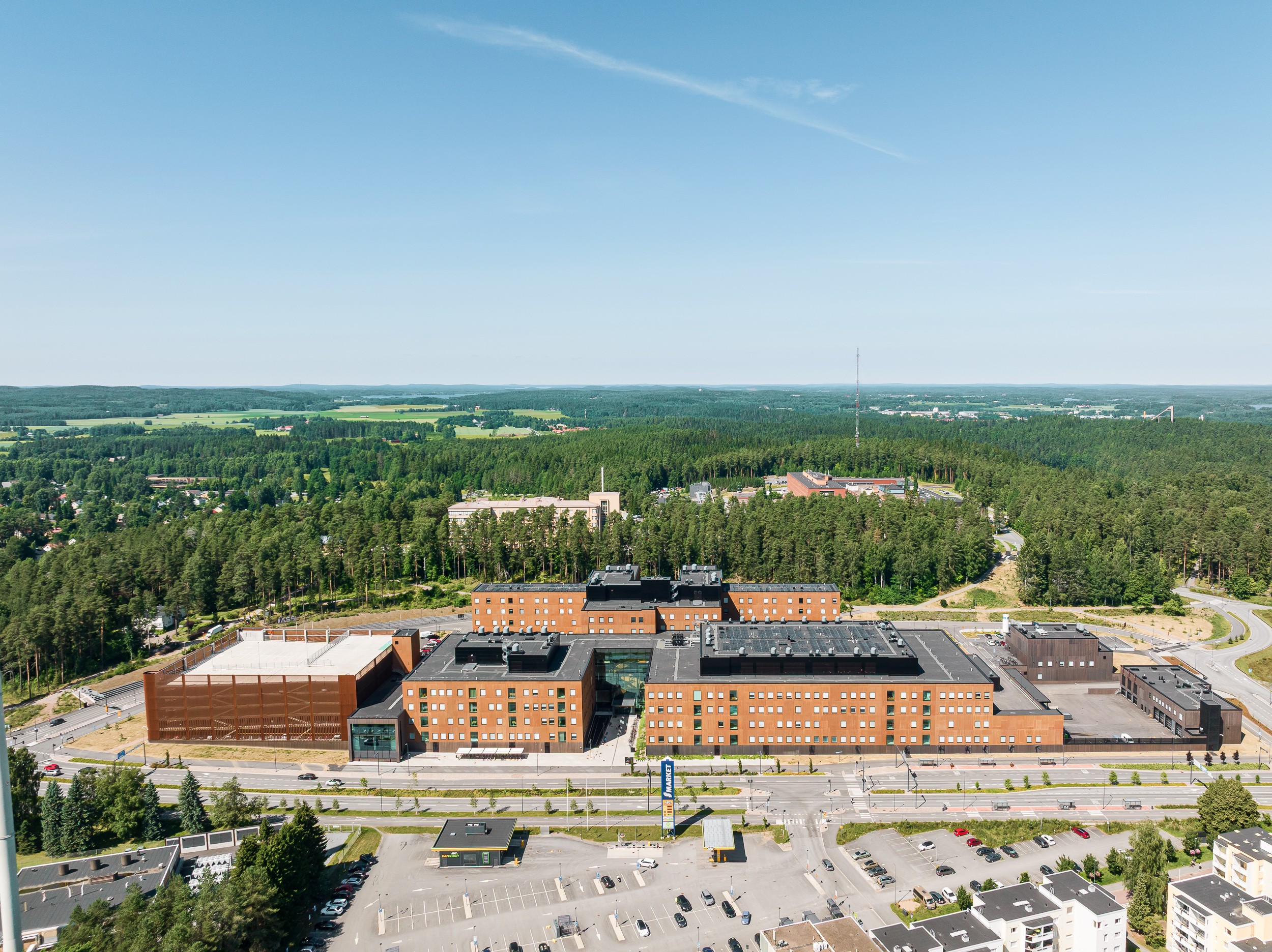 Ilmakuva suuresta punertavasta sairaalakokonaisuudesta, jota ympäröivät puut ja pysäköintialueet.