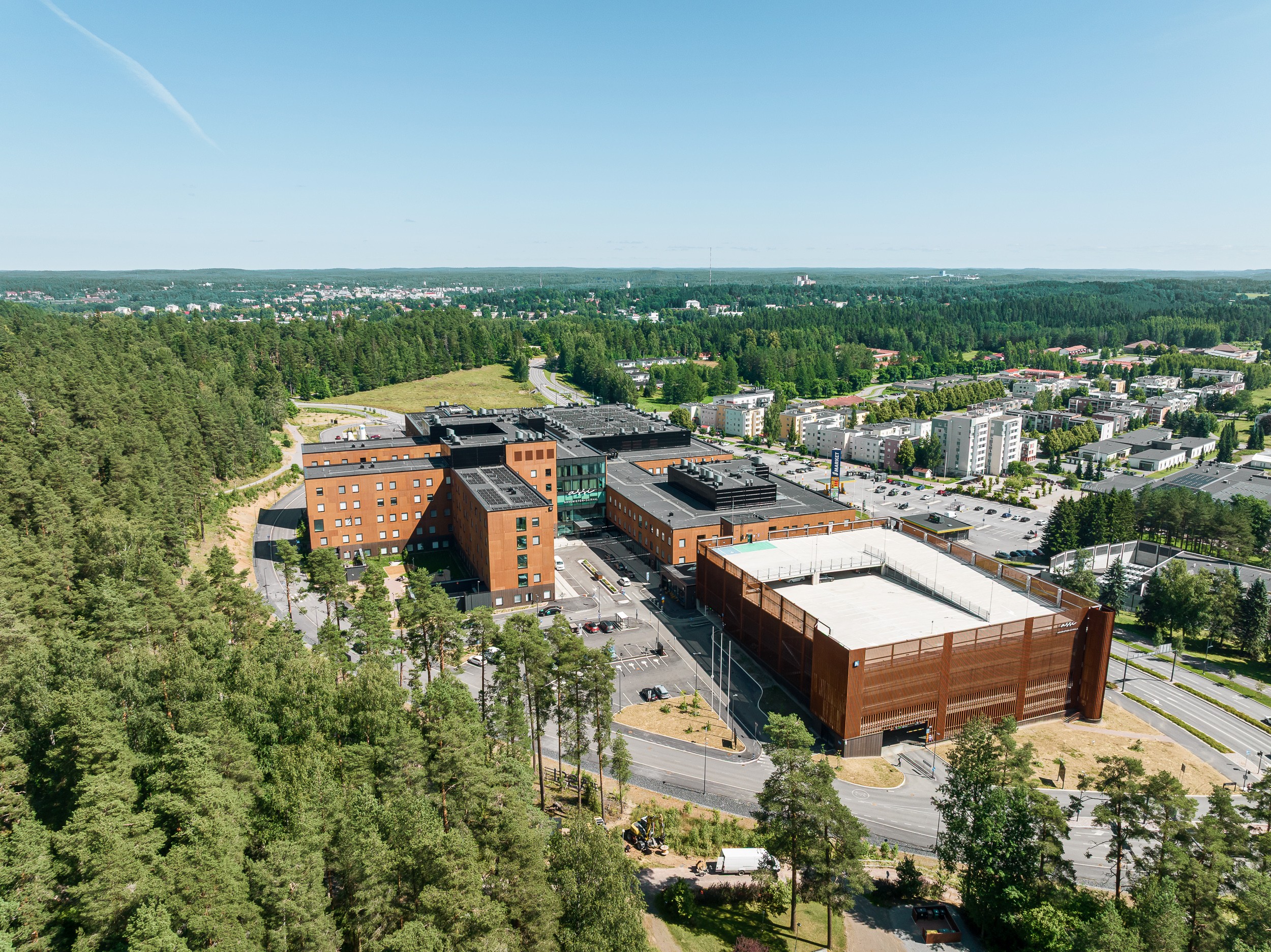 Ilmakuva punertavan värisestä sairaalasta, jota ympäröivät puut ja asuinrakennukset.