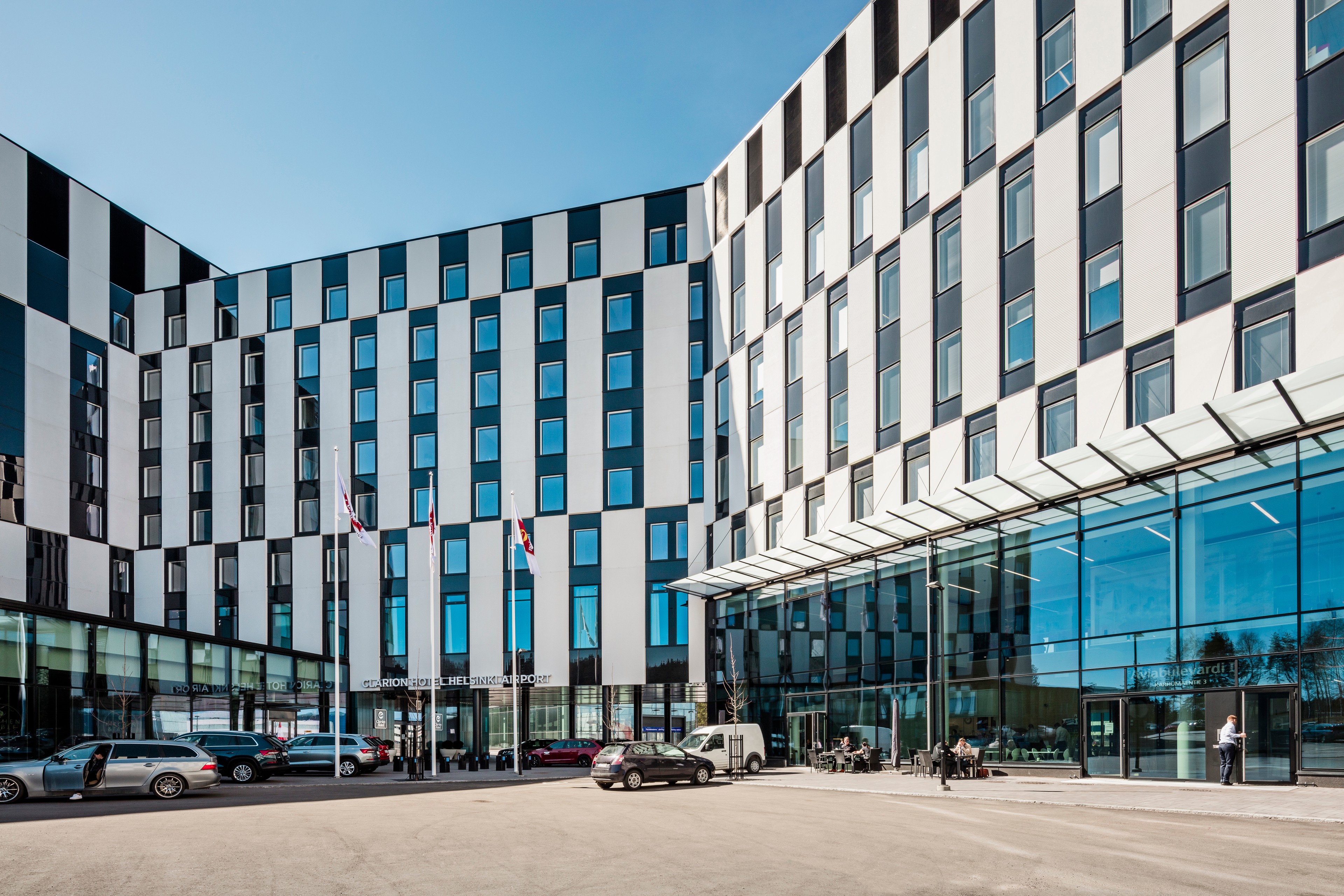 Clarion Hotel Helsinki Airport, sisäänkäynti Moderni hotelli graafisella lasijulkisivulla, jossa lasia, valkoisia paneeleita ja mustaa peltipintaa.