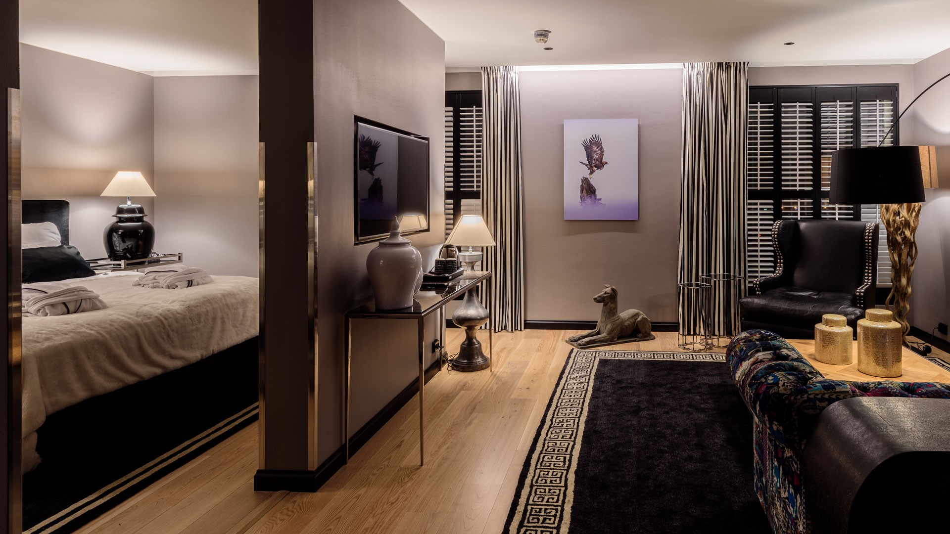 Tyylikäs moderni hotellihuone, jossa on elegantti sisustus, sisältäen viihtyisän istuinalueen ja hienostuneen valaistuksen.