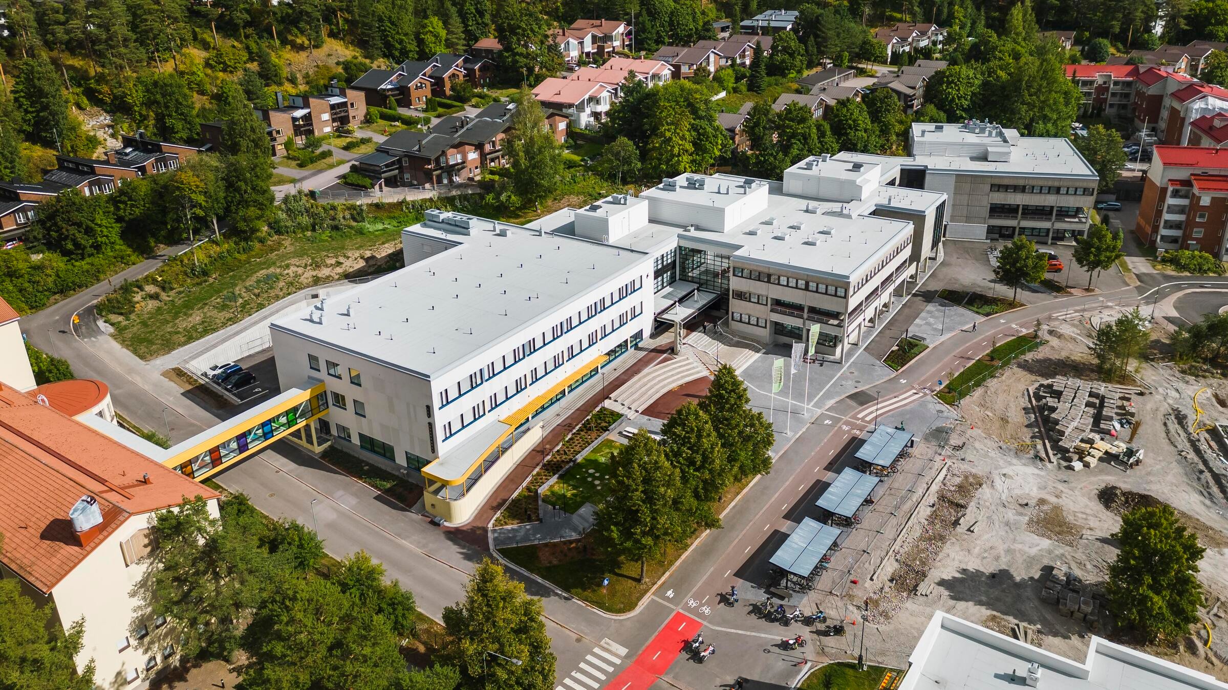 Ilmakuva modernista koulukompleksista, jota ympäröivät asuinalueet ja vihreät alueet.