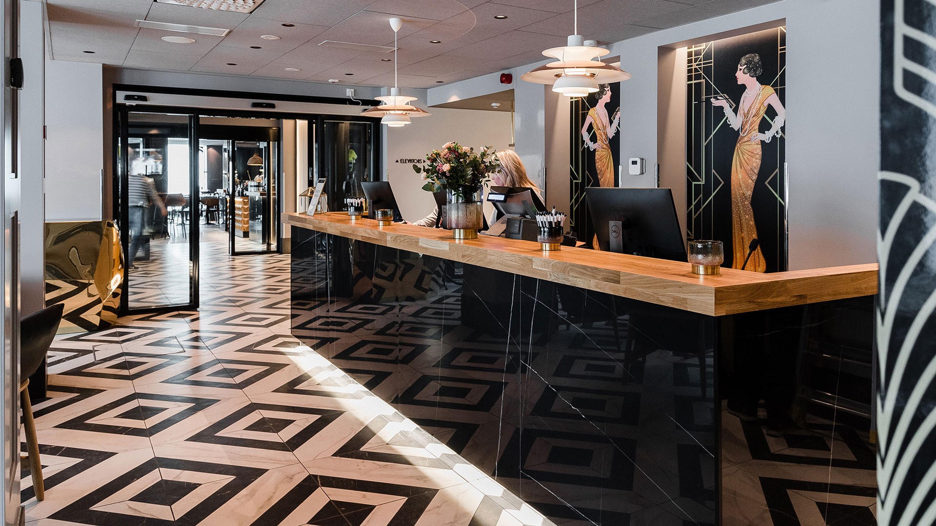 Hotellin vastaanotto siirrettiin Eerikinkadun puolelta Humalistonkadulle. Art deco -tyylinen hotellin aula, jossa on geometrinen laatoitettu lattia ja musta vastaanottotiski.