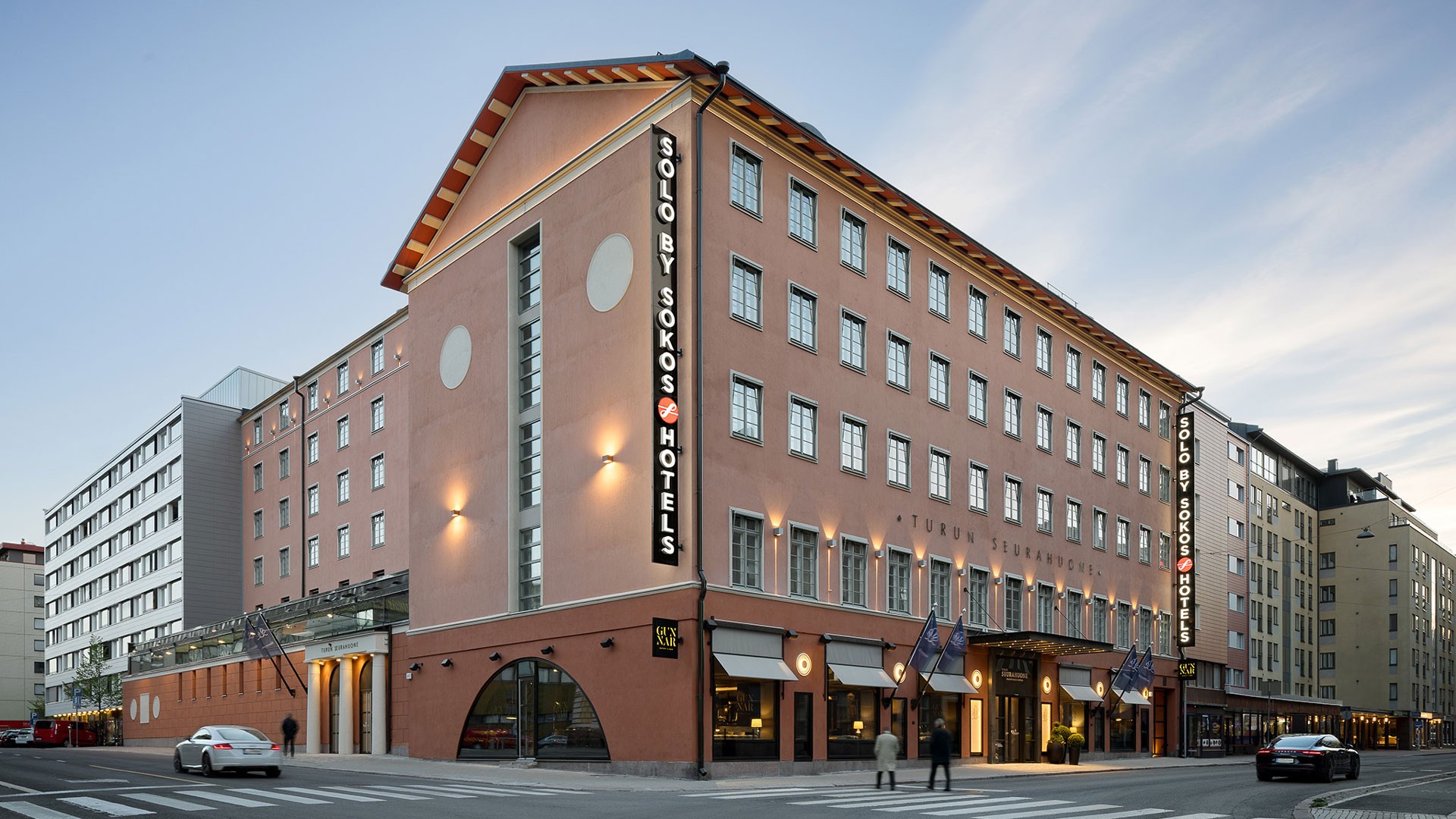 Turun Seurahuone on kokenut täydellisen peruskorjauksen. Julkisivut noudattelevat rakennuksen alkuperäisen aikakauden värimaailmaa. Ulkonäkymä Solo Sokos Hotelista, tyylikäs monikerroksinen rakennus vilkkaassa kaupungin kulmassa.