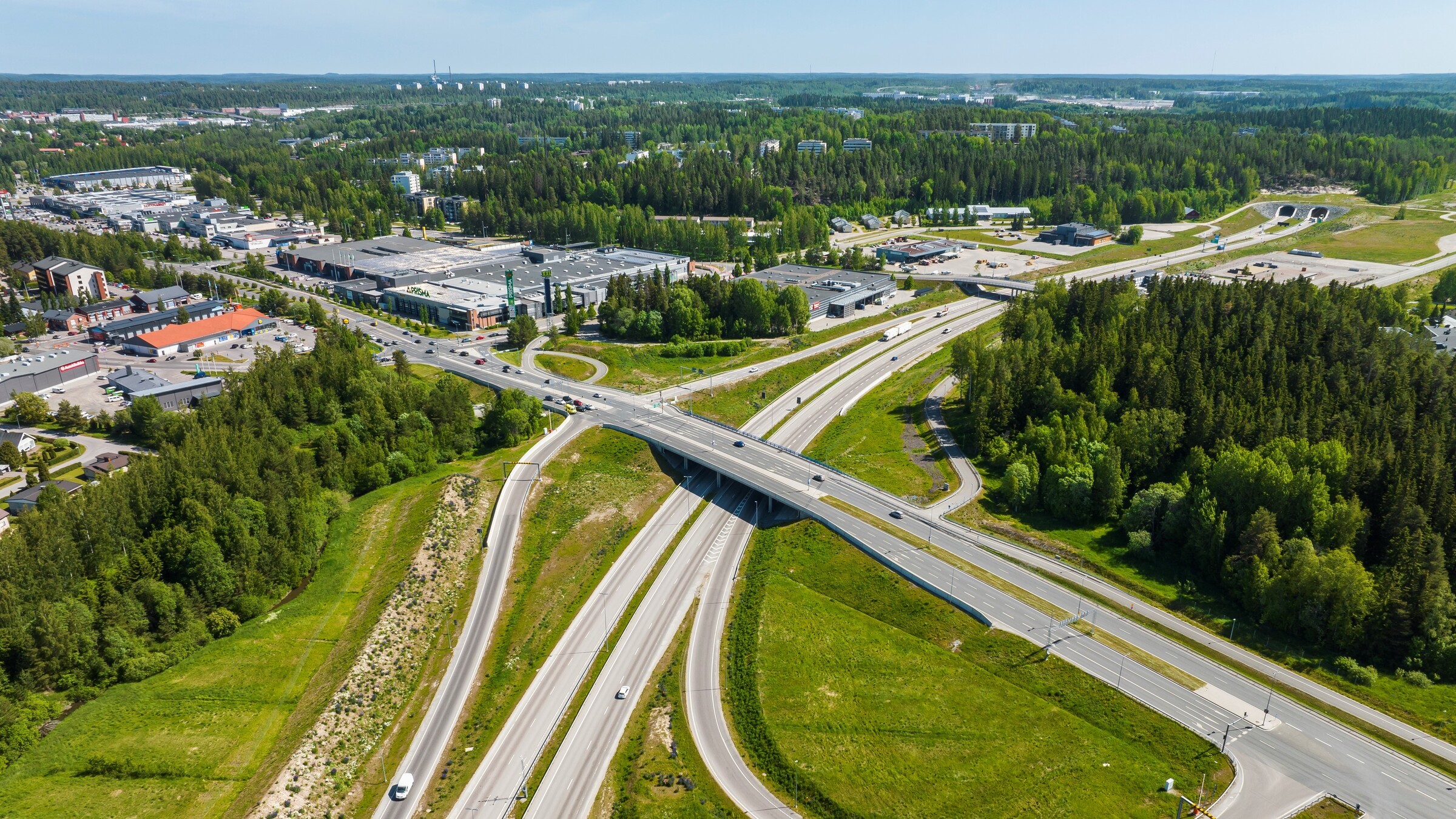 Ilmakuva moottoritien liittymästä, jota ympäröi vehreä kasvillisuus ja liikekiinteistöt.