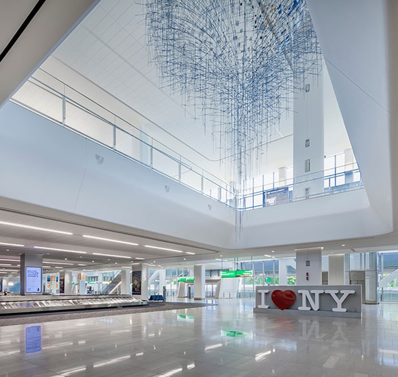 Spacious airport terminal with modern design, large skylight, and "I ❤️ NY" sign.