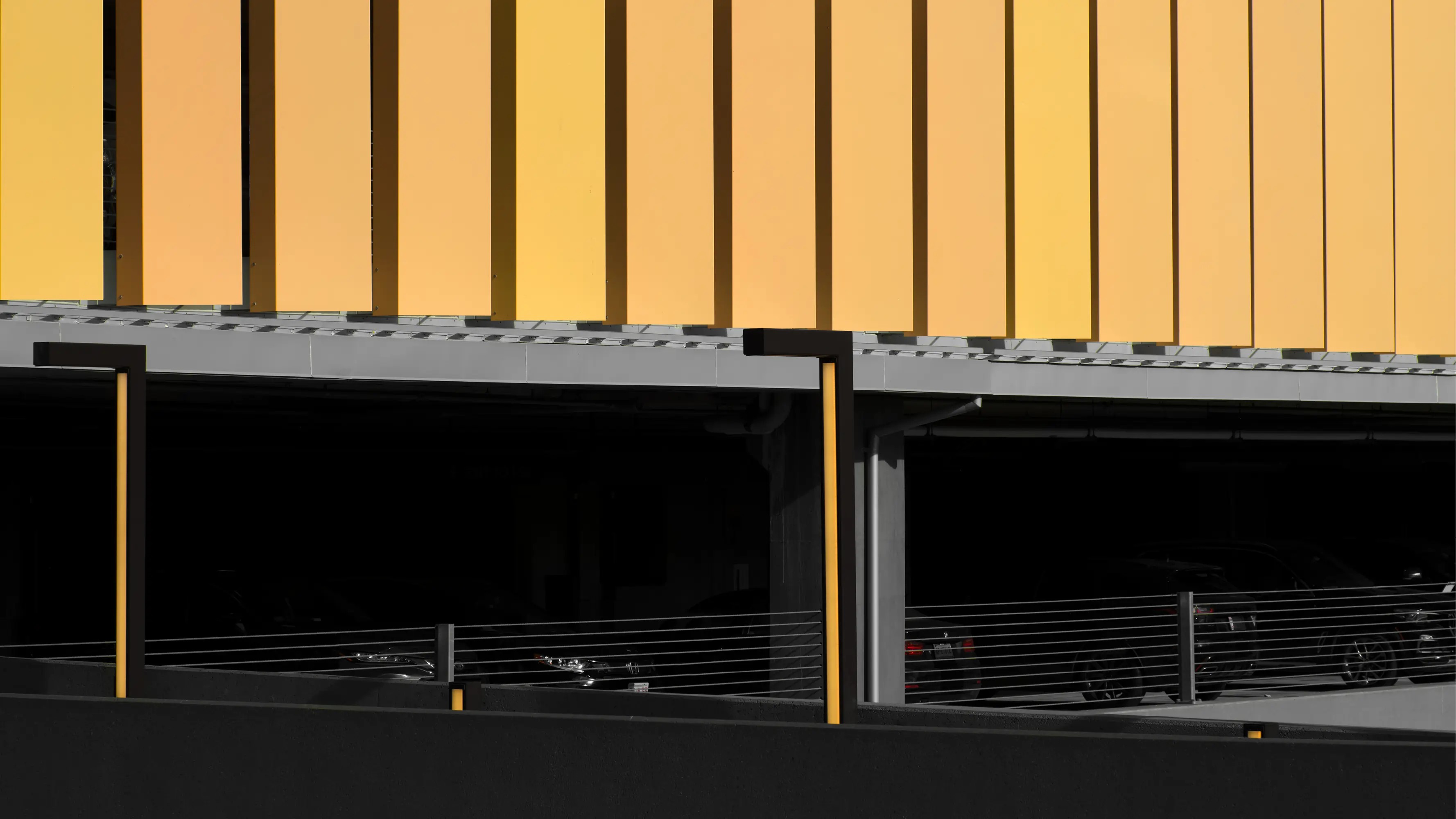 Modern parking garage with yellow vertical panels and sleek black fencing.