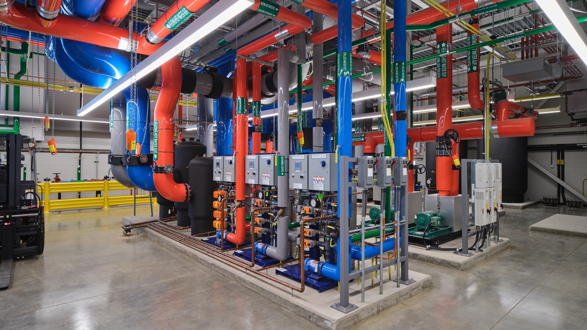 Industrial HVAC system with colorful insulated pipes and pumps Industrial HVAC system with colorful insulated pipes and control panels in a mechanical room.