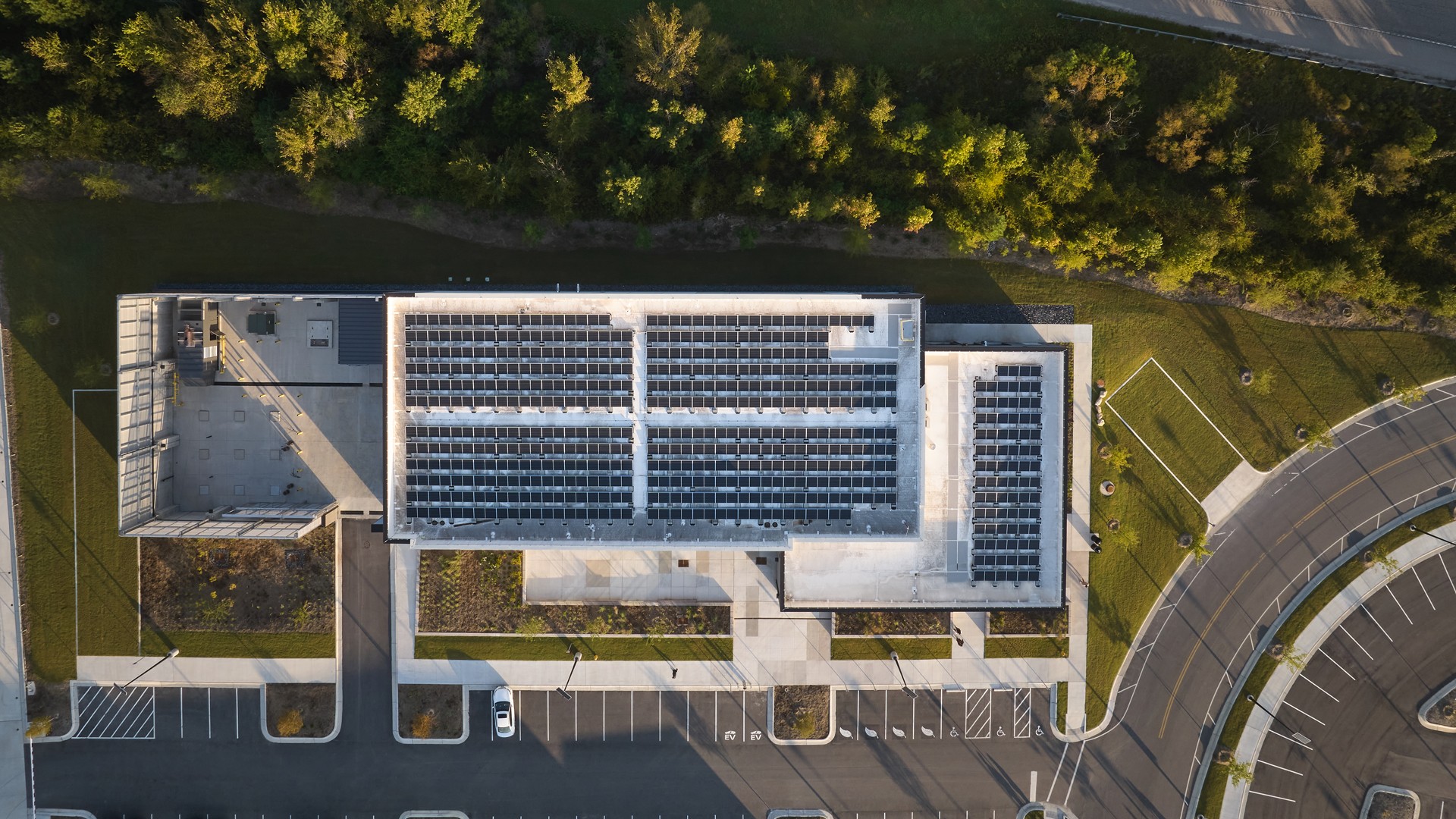 Aerial view of building rooftop with solar panels installation Aerial view of a commercial building with solar panels on the roof and parking lot.