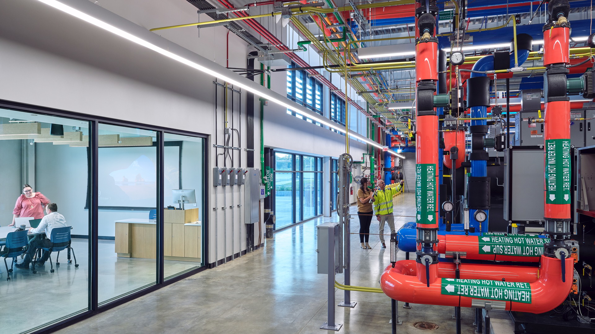 Modern Industrial Facility with Classroom and Machinery Setup Modern industrial facility with large heating system pipes and engineers inspecting it.