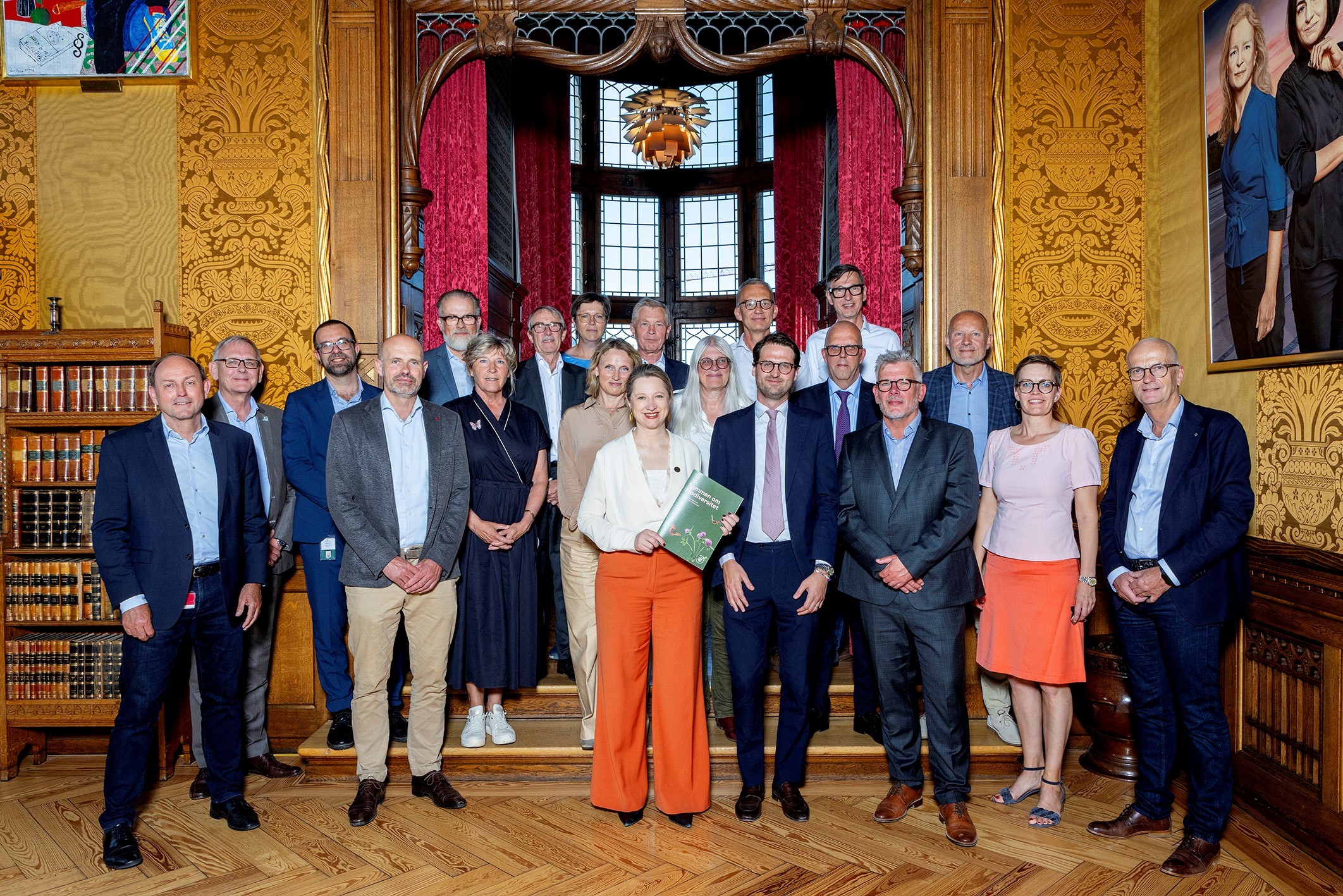 Group of professionally dressed people posing in an elegant room with wooden floors.