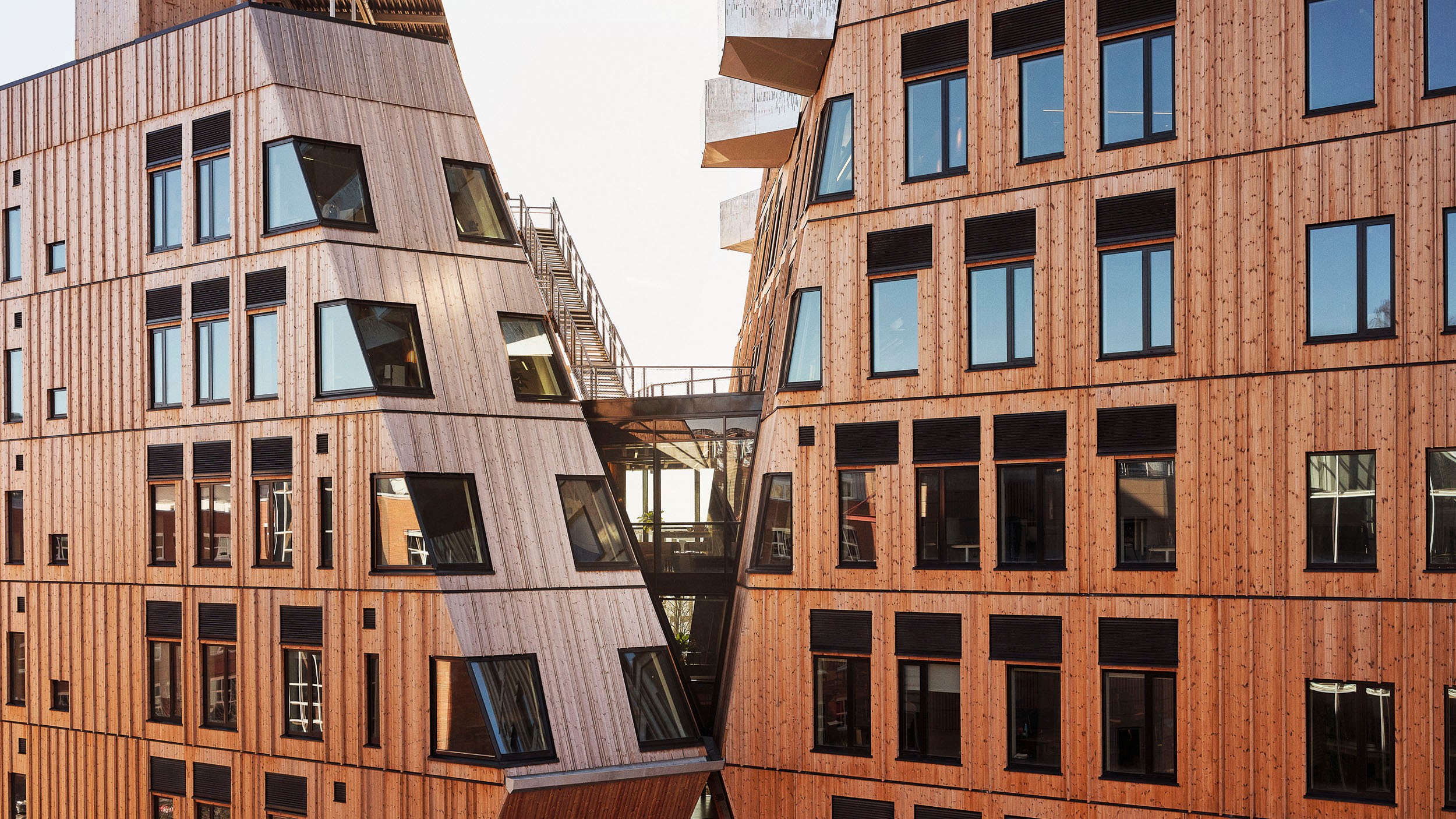 Modern wooden buildings with large windows and angled architectural design in daylight.