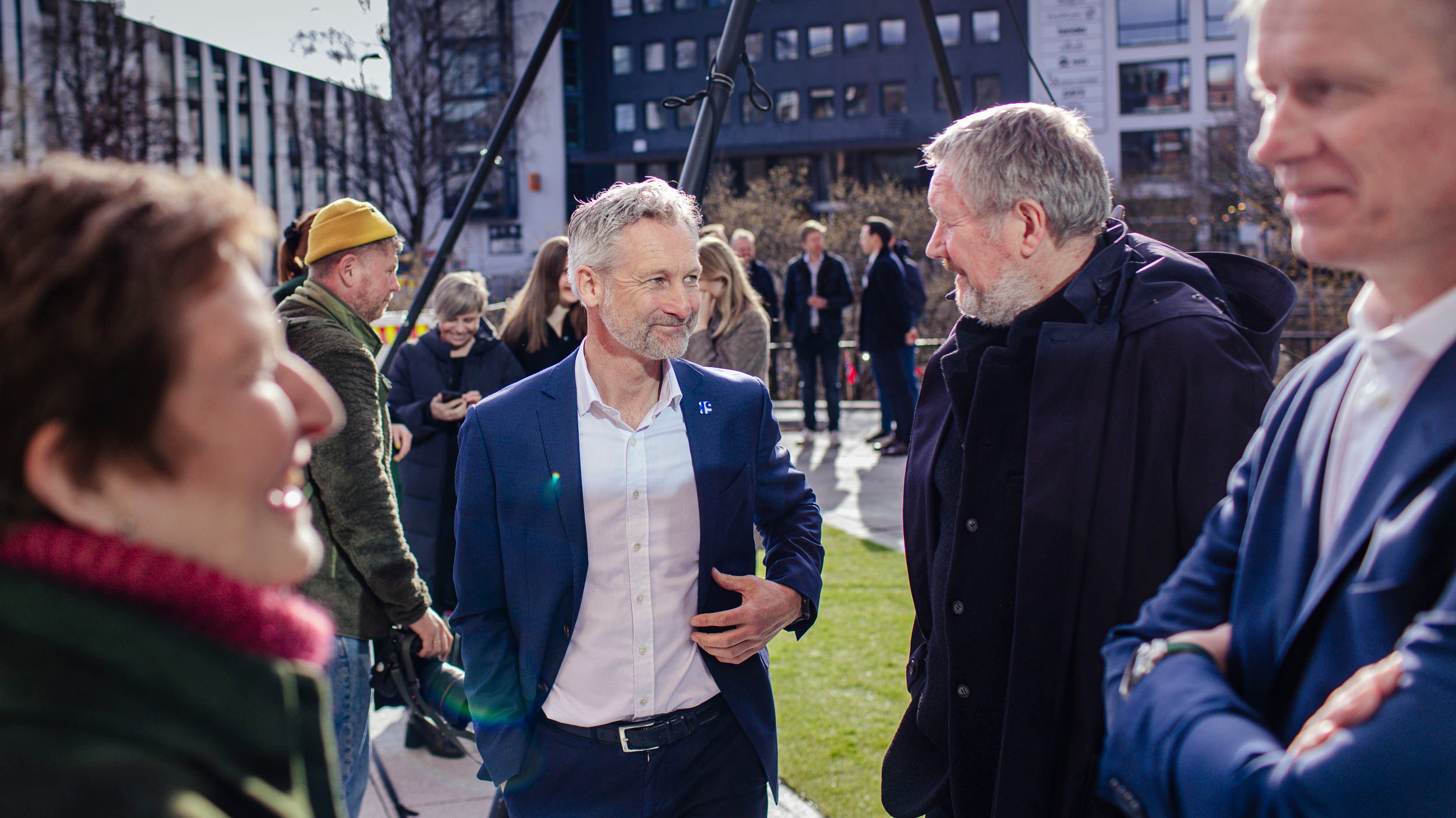 Group of professionally dressed people engaged in outdoor business conversation.