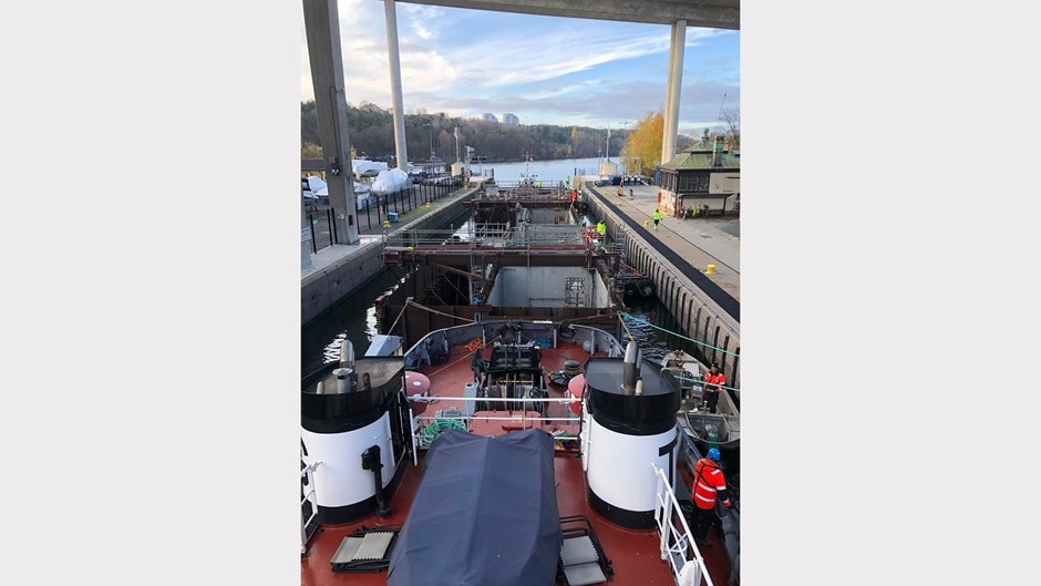 Lastfartyg dockat i en slusskammare med arbetare och vattenväg i bakgrunden.